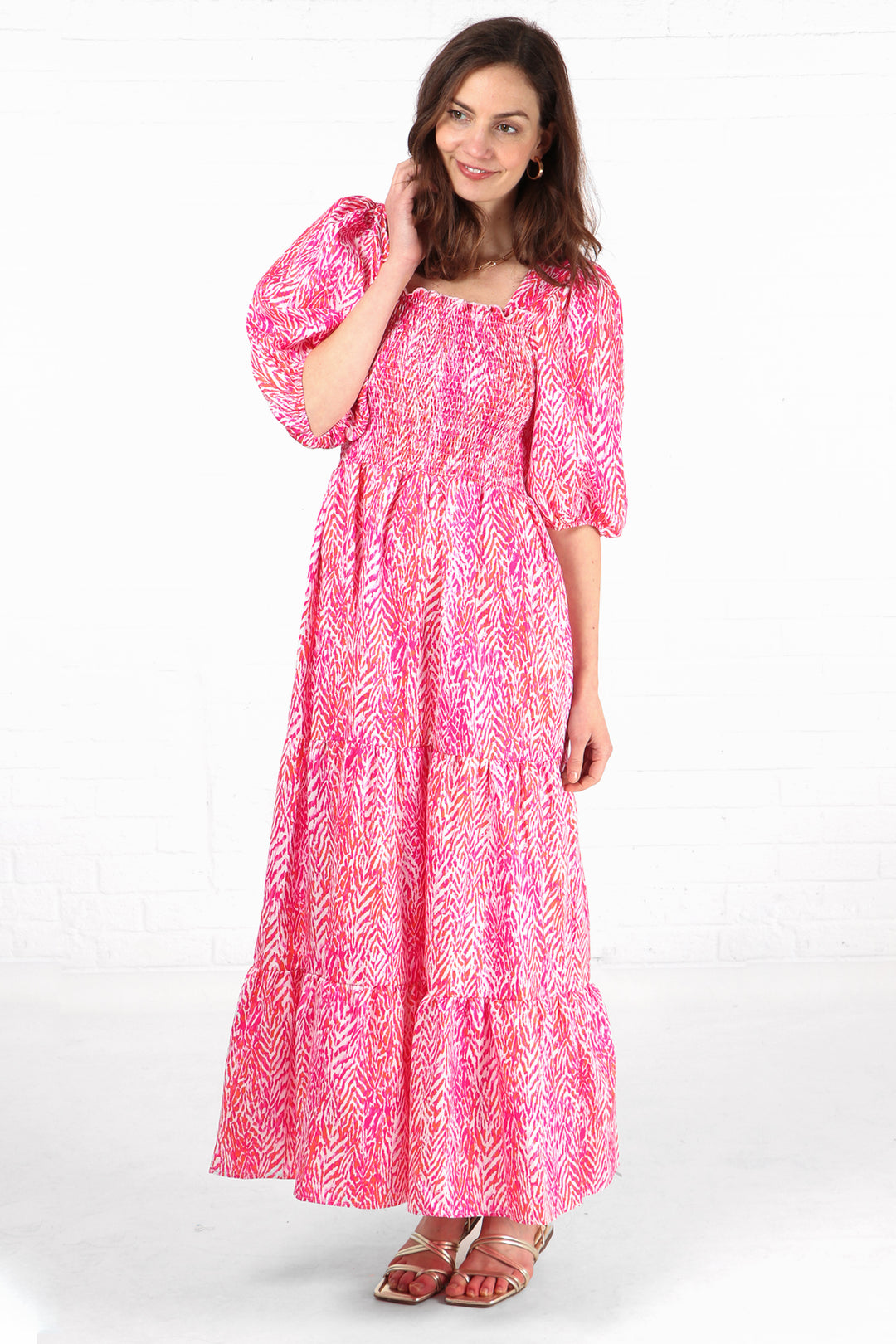model wearing a maxi length puff sleeve tired milkmaid dress with an all over pink chevron pattern