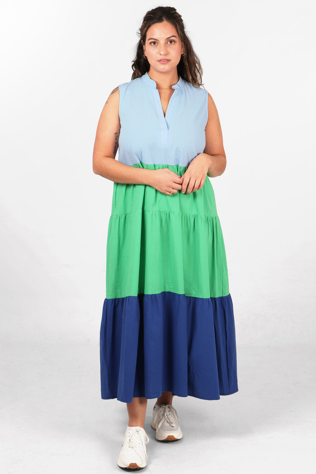 model wearing a blue and green colourblock striped tirered midaxi dress, the dress is sleeveless and has a grandand collar