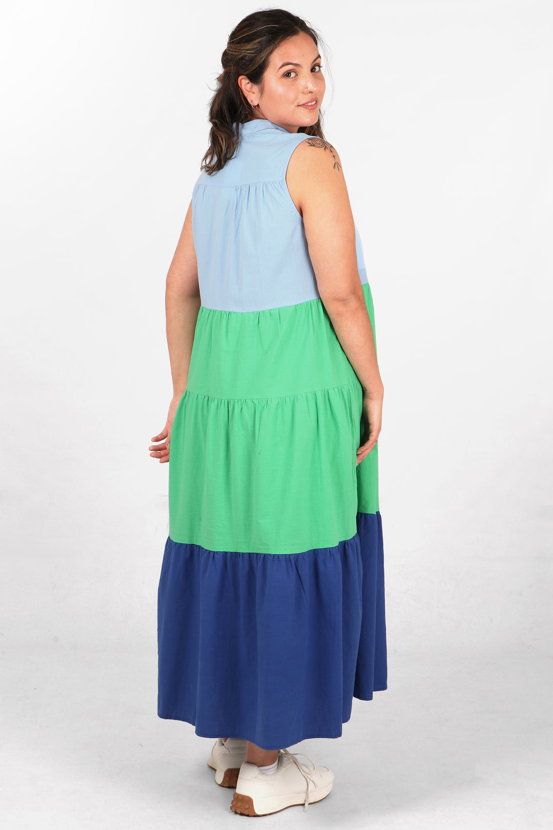 model showing the back of the dress, showing the all over colour block stripe pattern and long tiered skirt