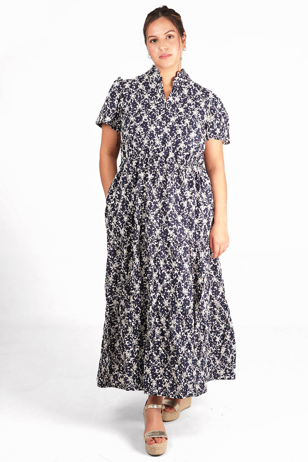 model wearing a maxi cotton dress with an all over floral broderie anglaise pattern, the dress is navy blue and white with short sleeves