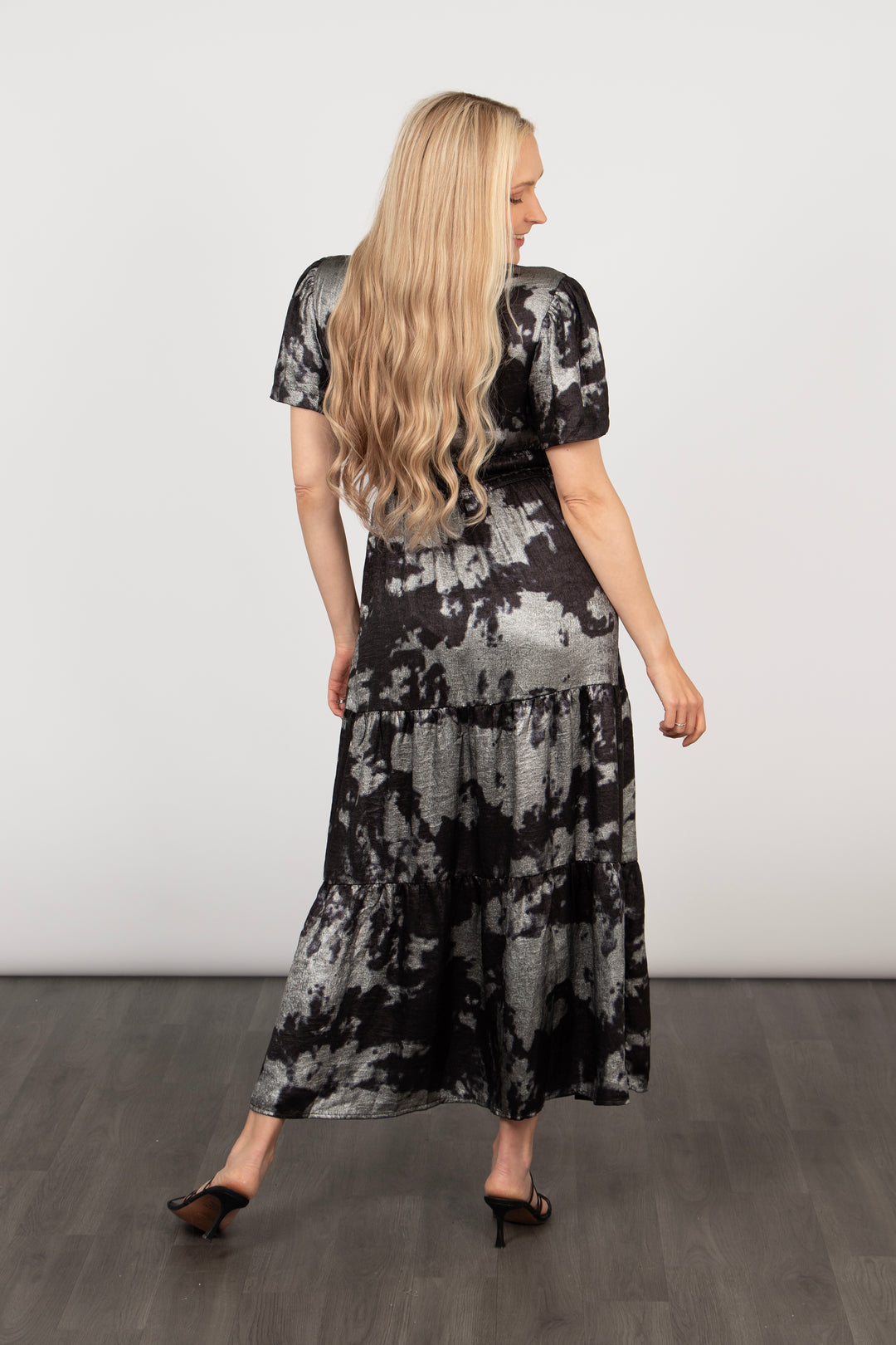 model showing the back of the dress, showing the all over pattern and the tiered hem. the dress is long and falls at the ankle