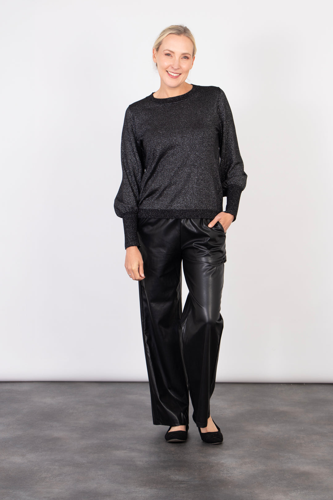 model showing that the black faux leather trousers have pockets on the side