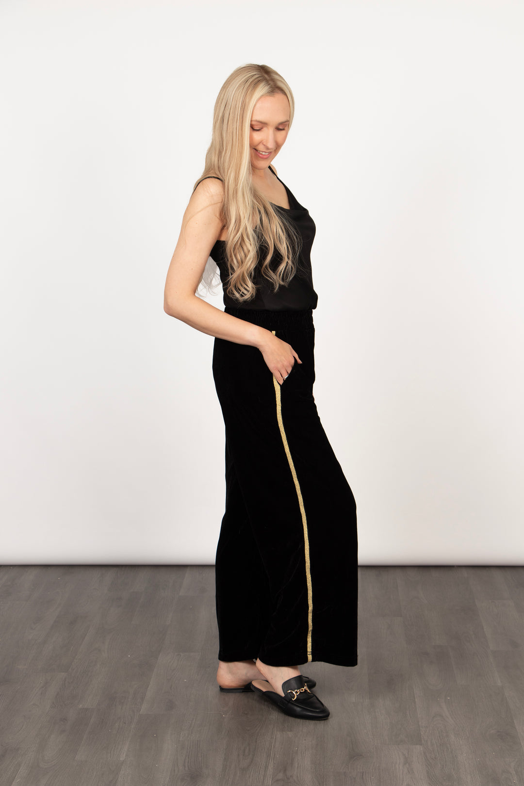 model showing a side view of the trousers, showing the gold glitter stripe running the full length of the trousers