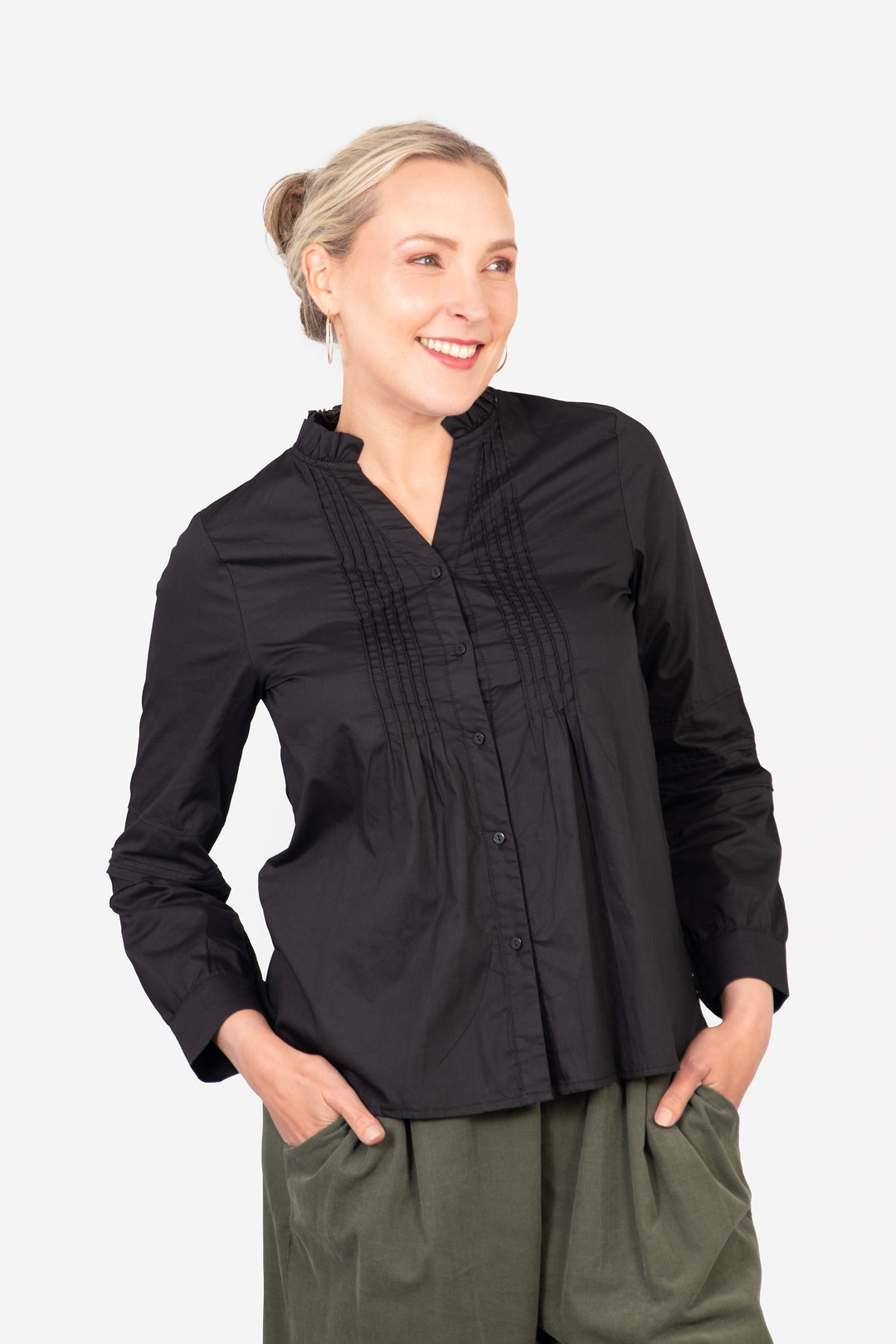 model wearing a slim fitting black cotton shirt, the shirt has pleats on the front and has button front closure