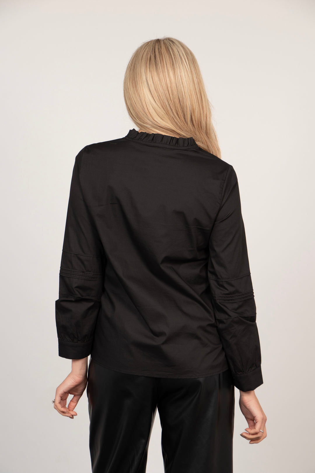 model showing the back of the shirt, it is plain black, the ruffled collar is visible
