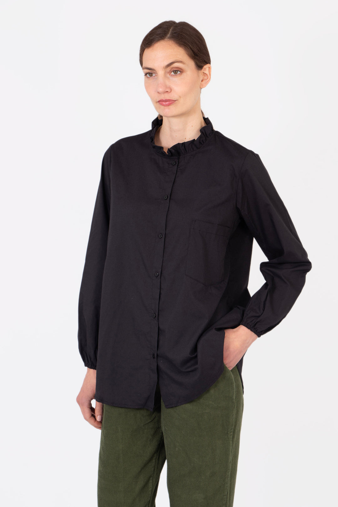 model wearing a plain black relaxed fitting cotton shirt with a frilled collar and long sleeves.