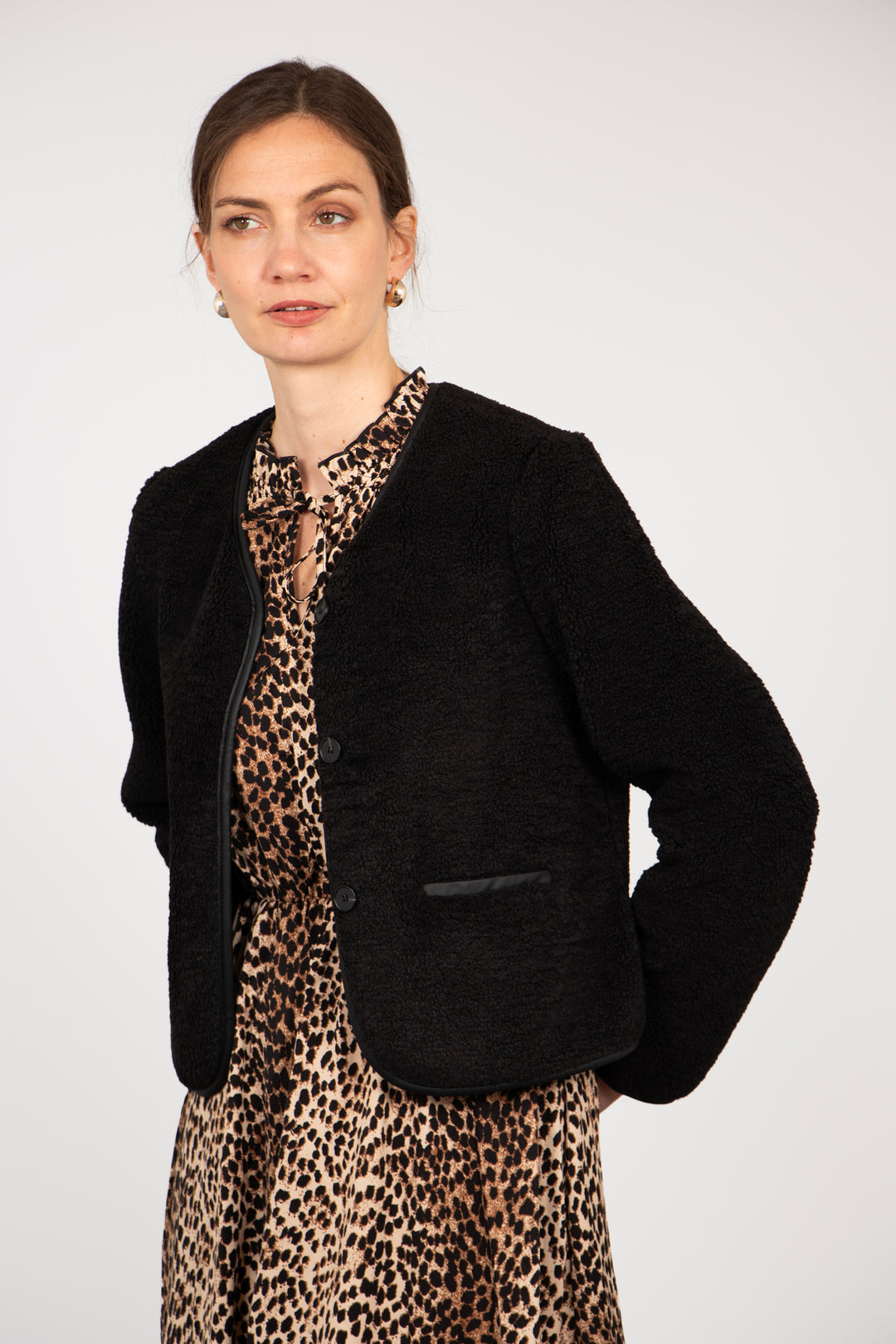 model wearing a black borg fleece jacket with a v-neck and button front