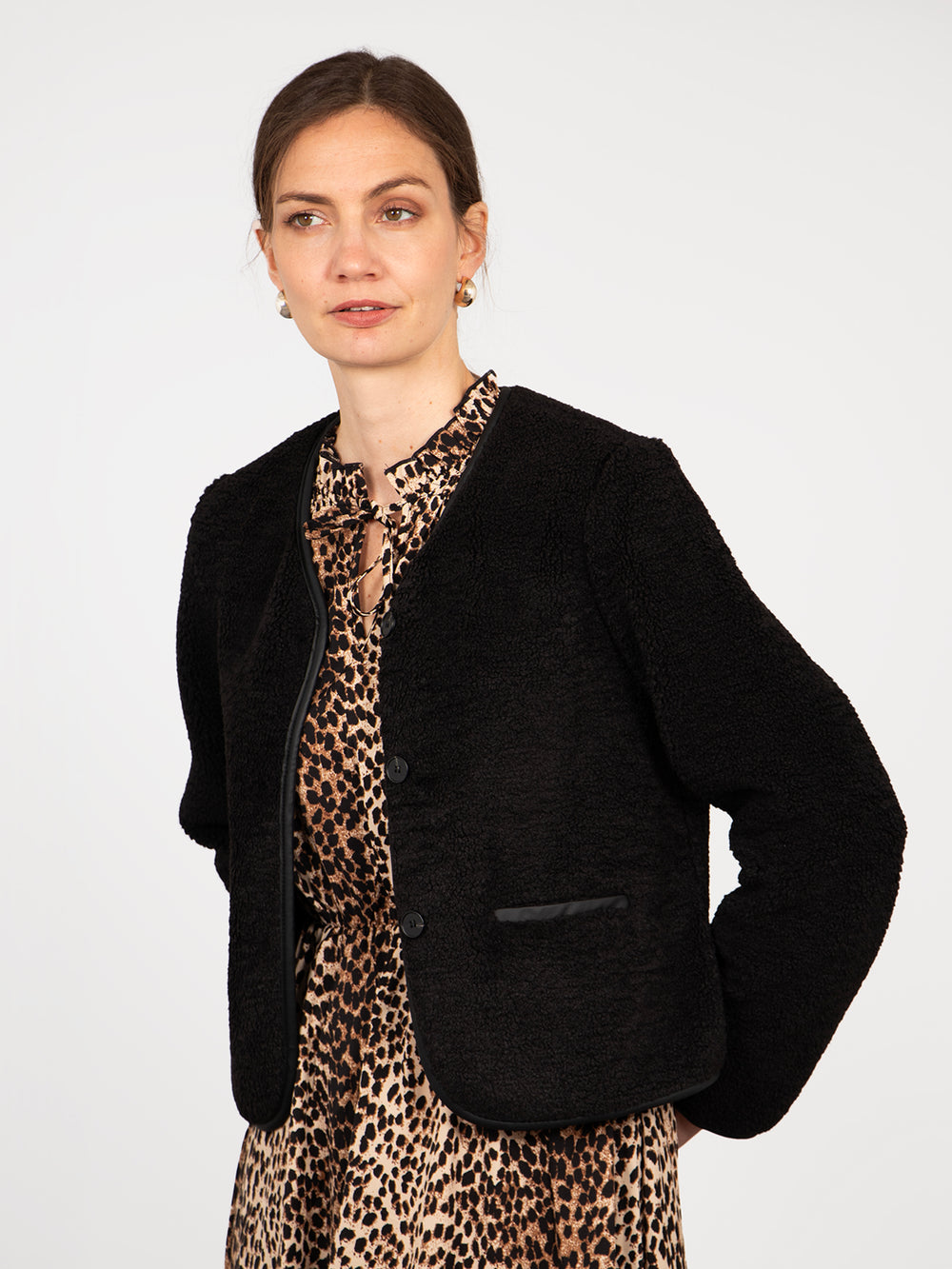 model wearing a black borg fleece jacket with a v-neck and button front