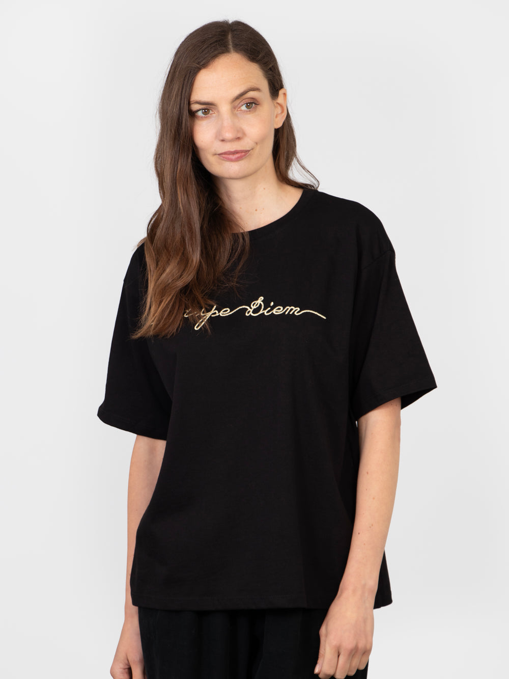 model wearing a black cotton t-shirt with the words, carpe diem, embroidered in gold on the front