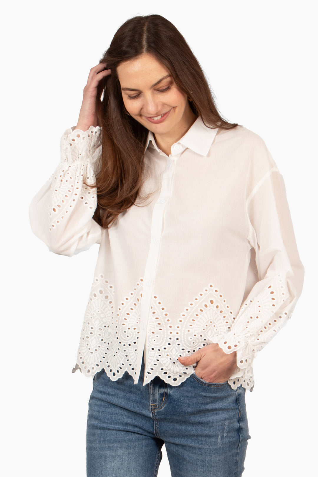 model wearing a lightweight white cotton shirt with a detailed broderie anglaise design on the cuffs and lower quarter of the bodice.