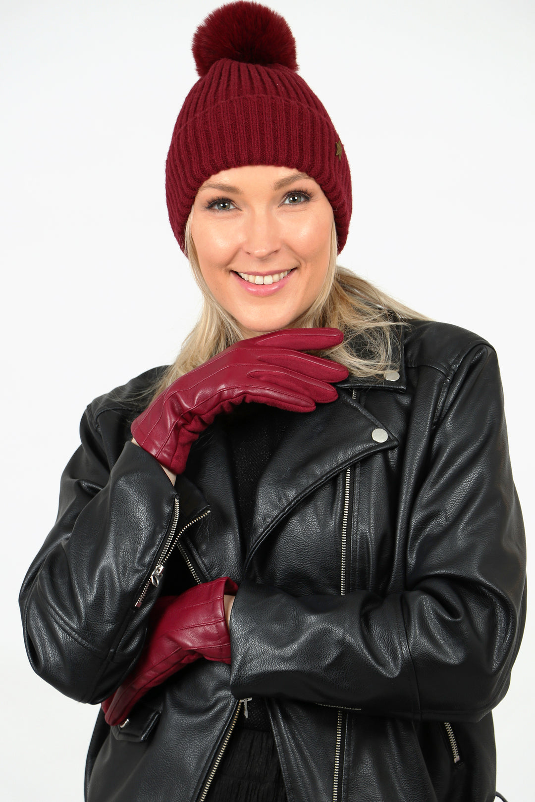 model wearing berry red faux leather touch screen gloves with a matching red beanie hat