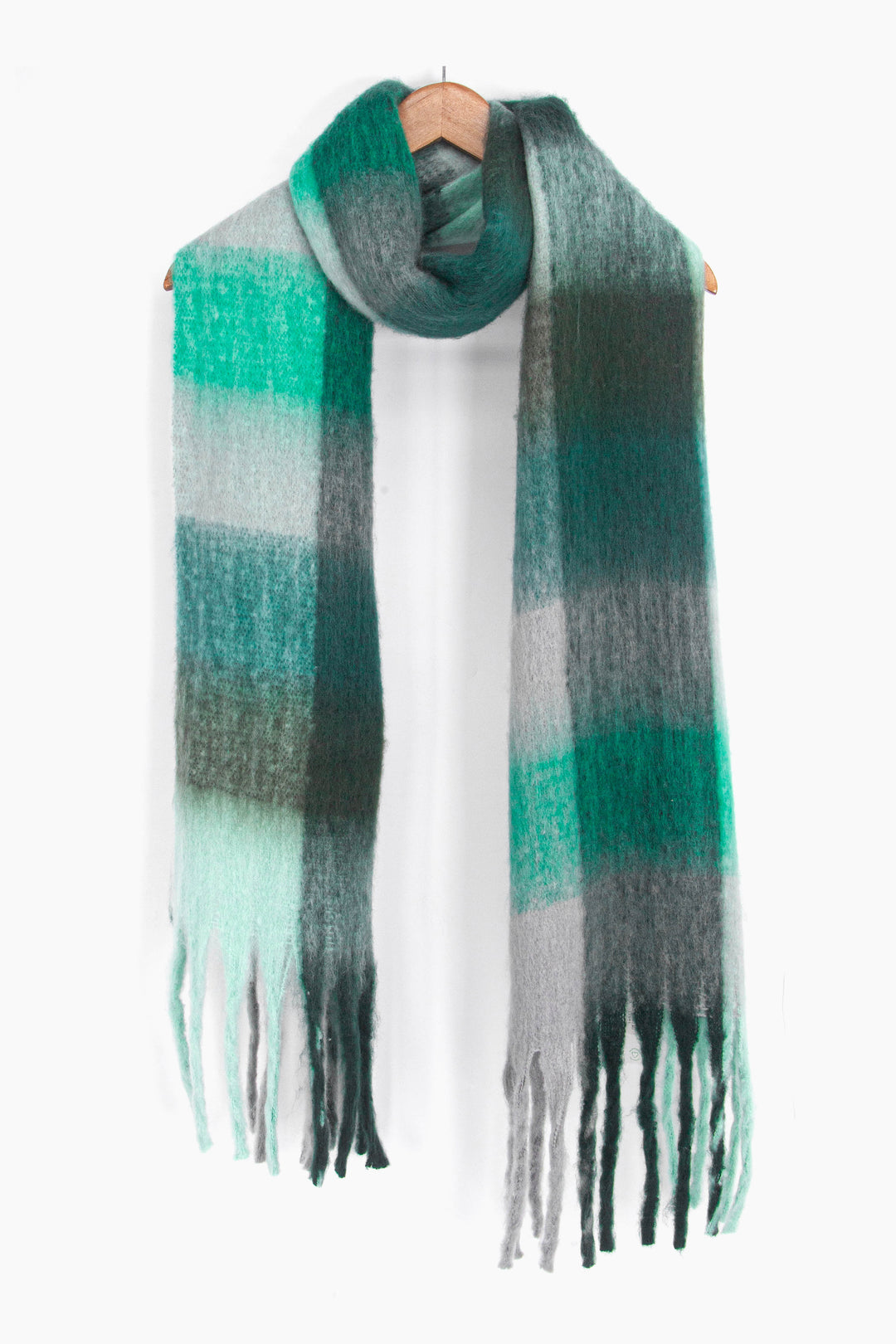 showing the teal and green square colour block winter scarf draped around a coat hanger, showing how it would look when worn.