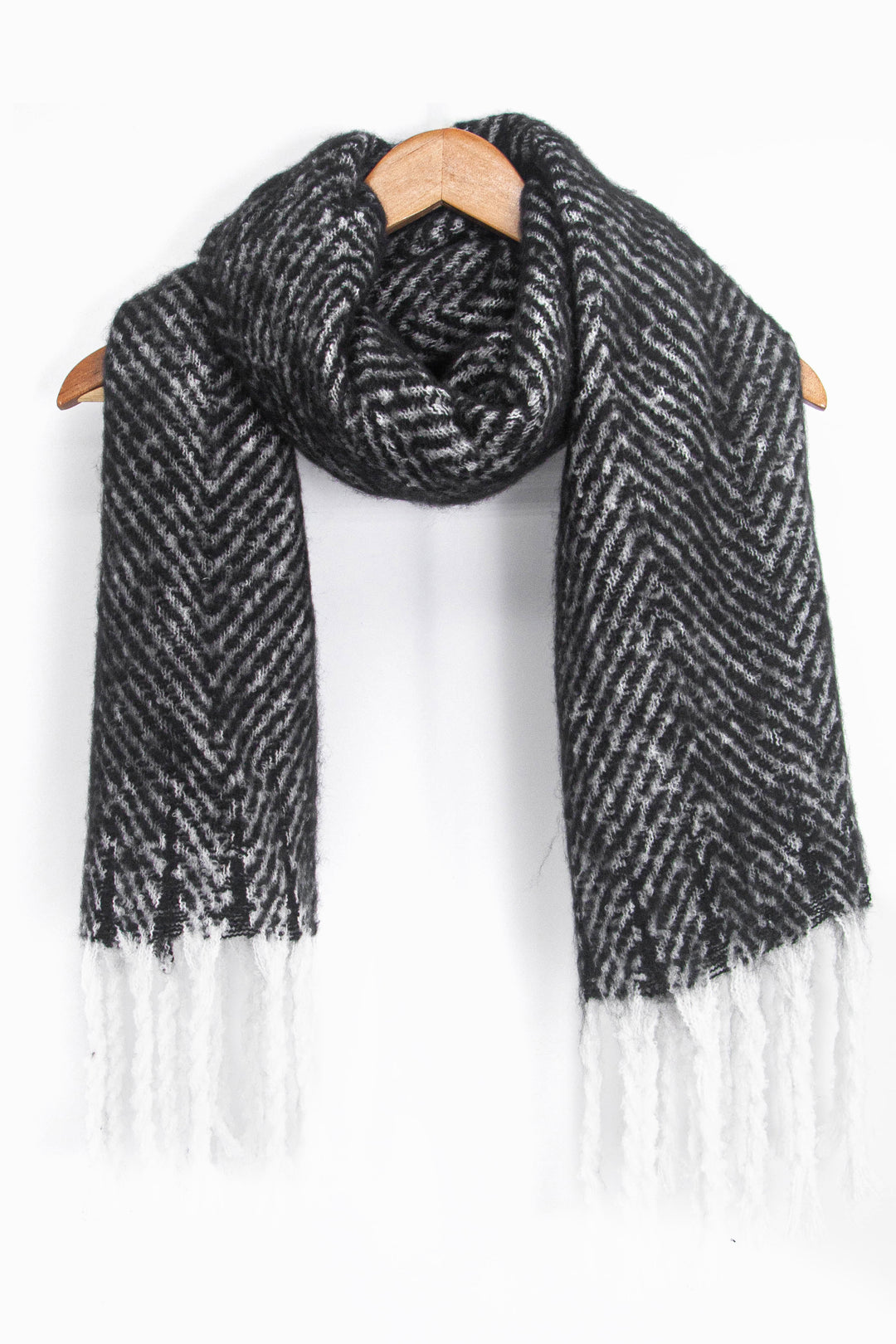 showing the black and white herringbone pattern winter scarf draped around a coat hanger, showing how it would look when worn.