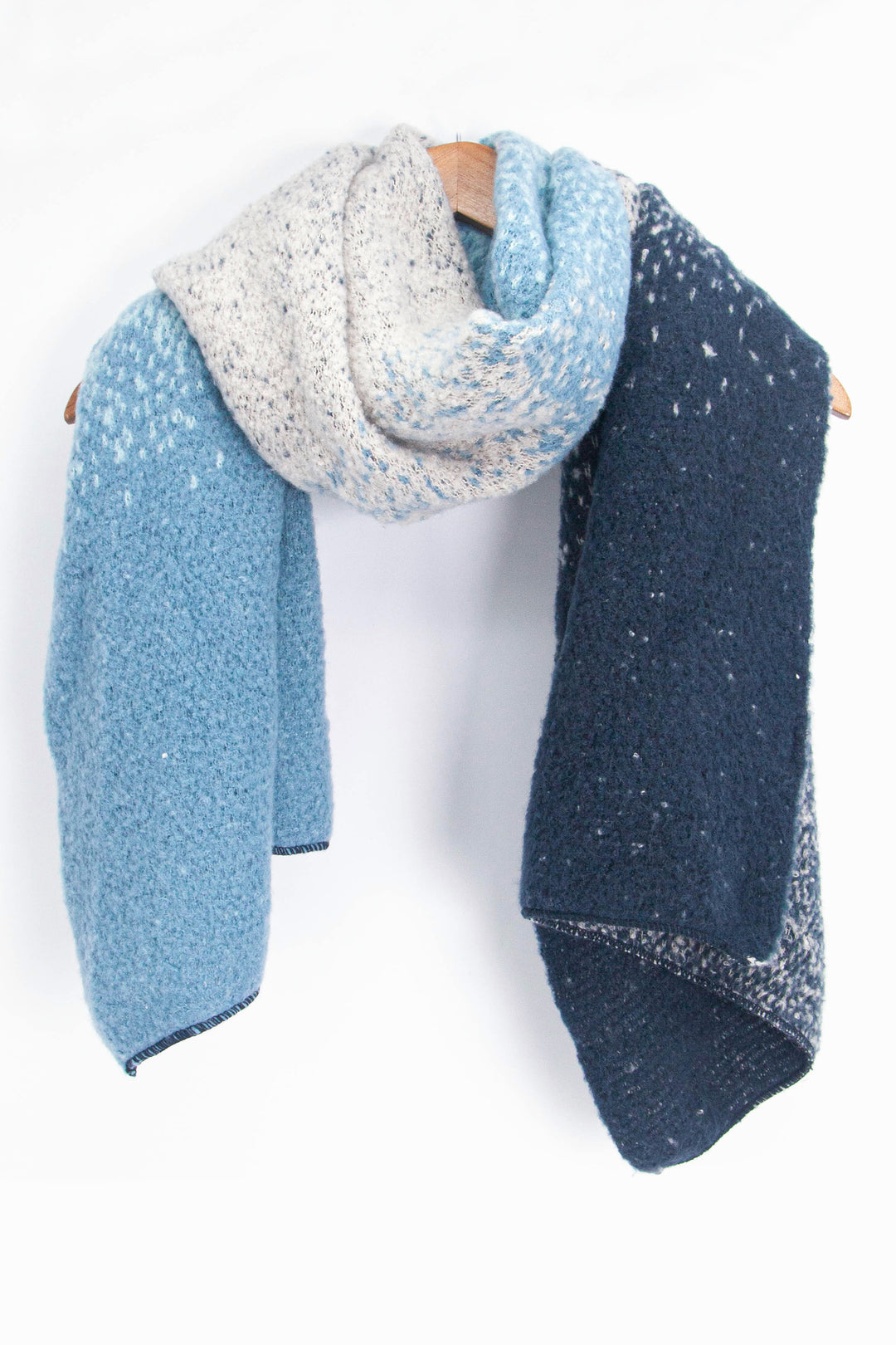 showing the blue ombre winter scarf draped around a coat hanger, showing how it would look when worn.