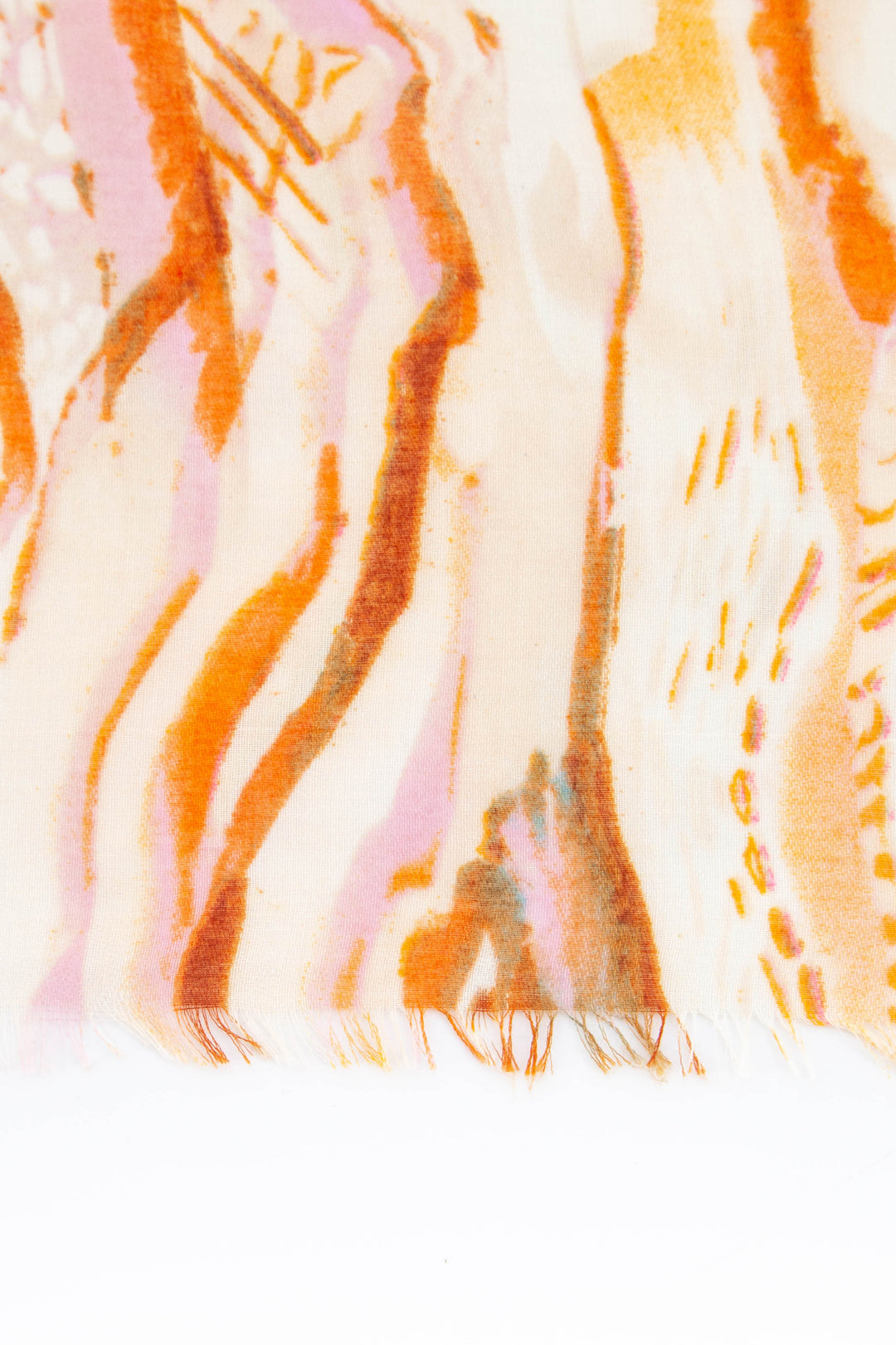 close up of the fringed edge and gold foil accents on the lightweight orange scarf