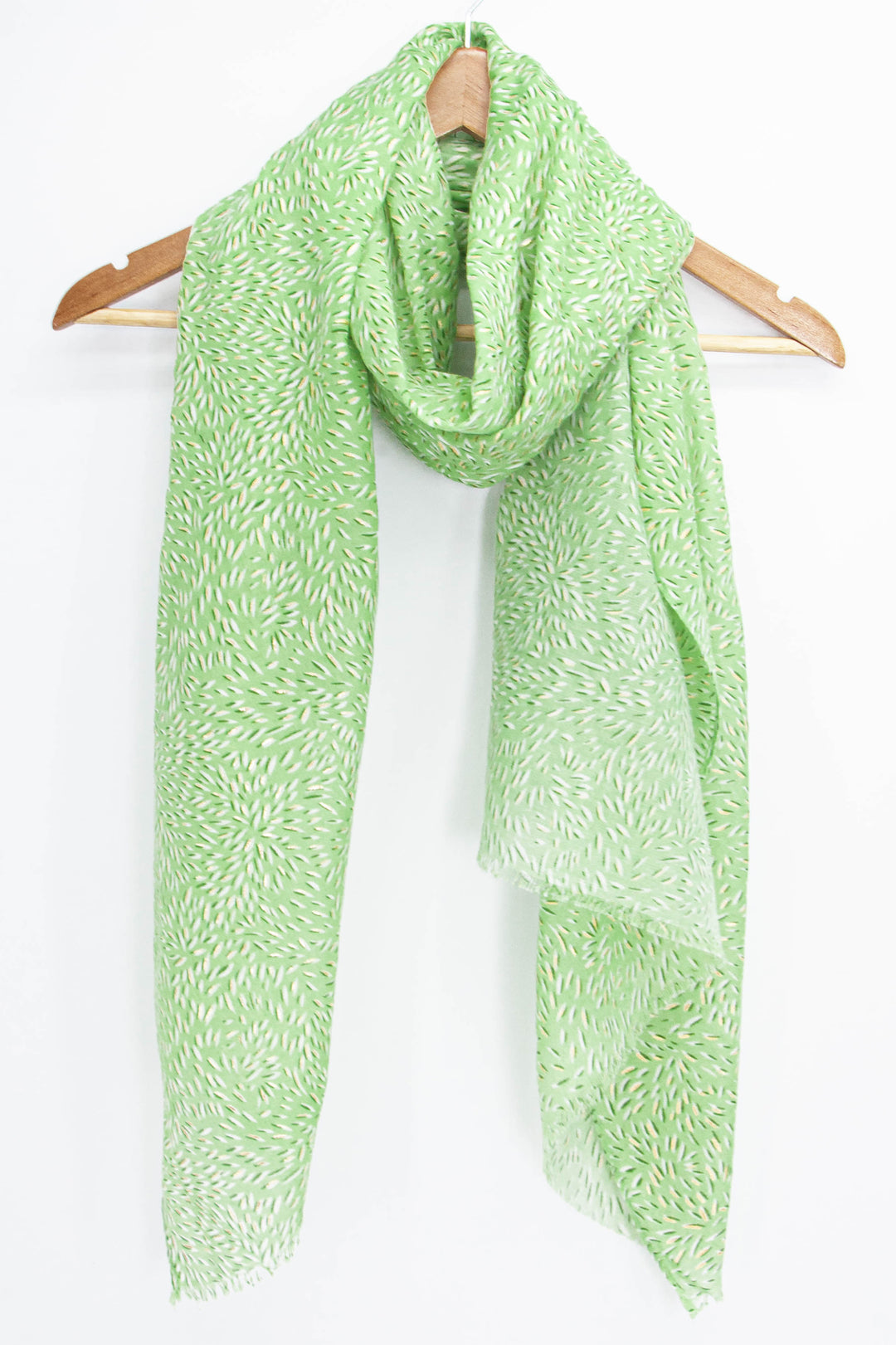 green summer scarf with an all over floral petal pattern draped around a coat hanger