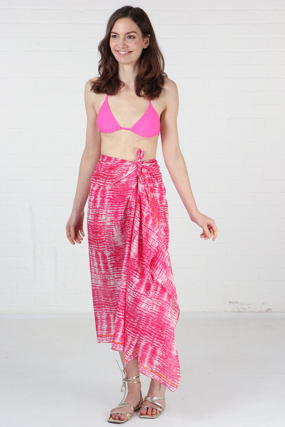 model wearing a pink cotton tie dye scarf as a beach sarong