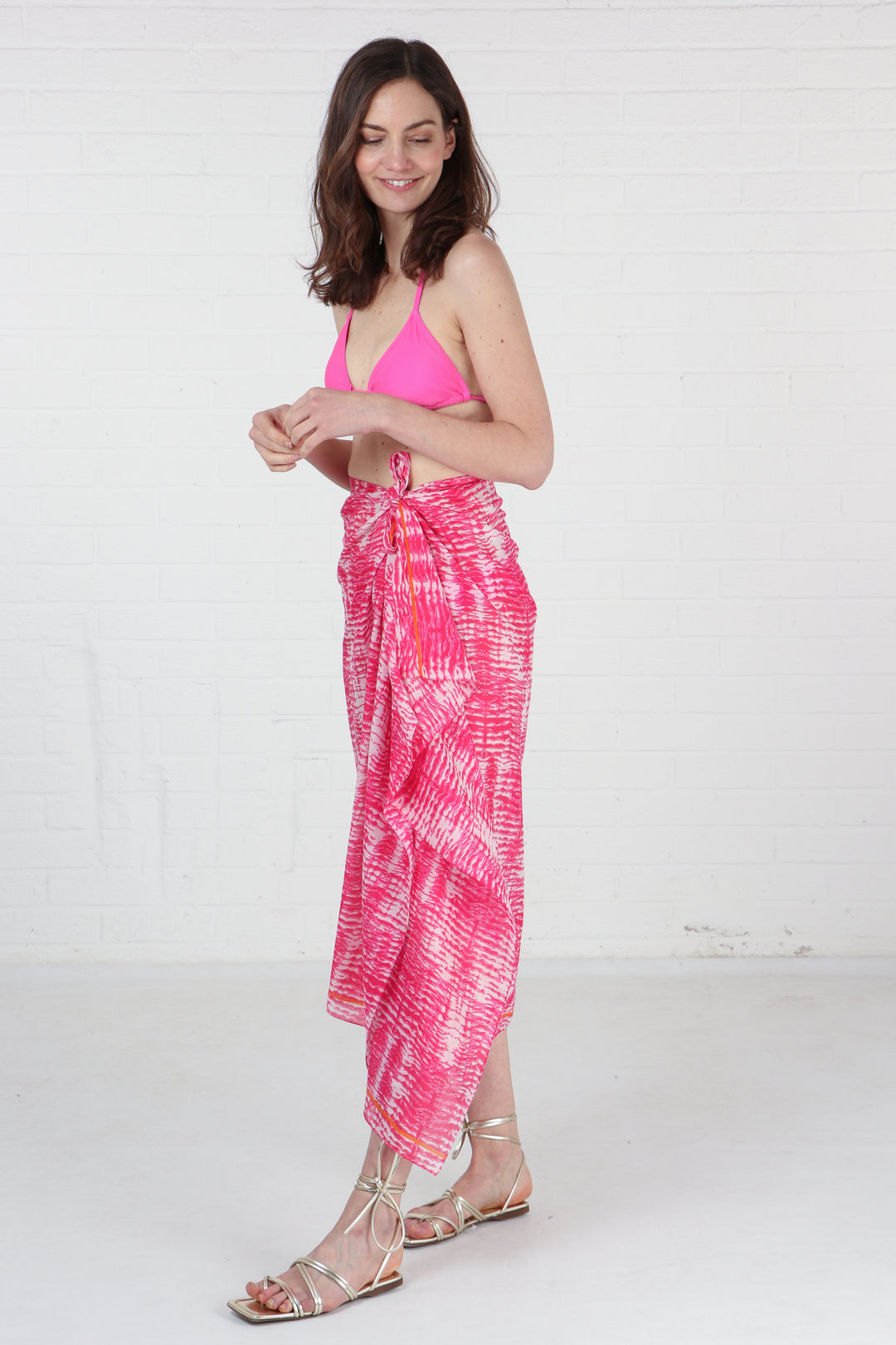pink tie scarf tied around the waist of a model, showing that this can be worn as a beach coverup