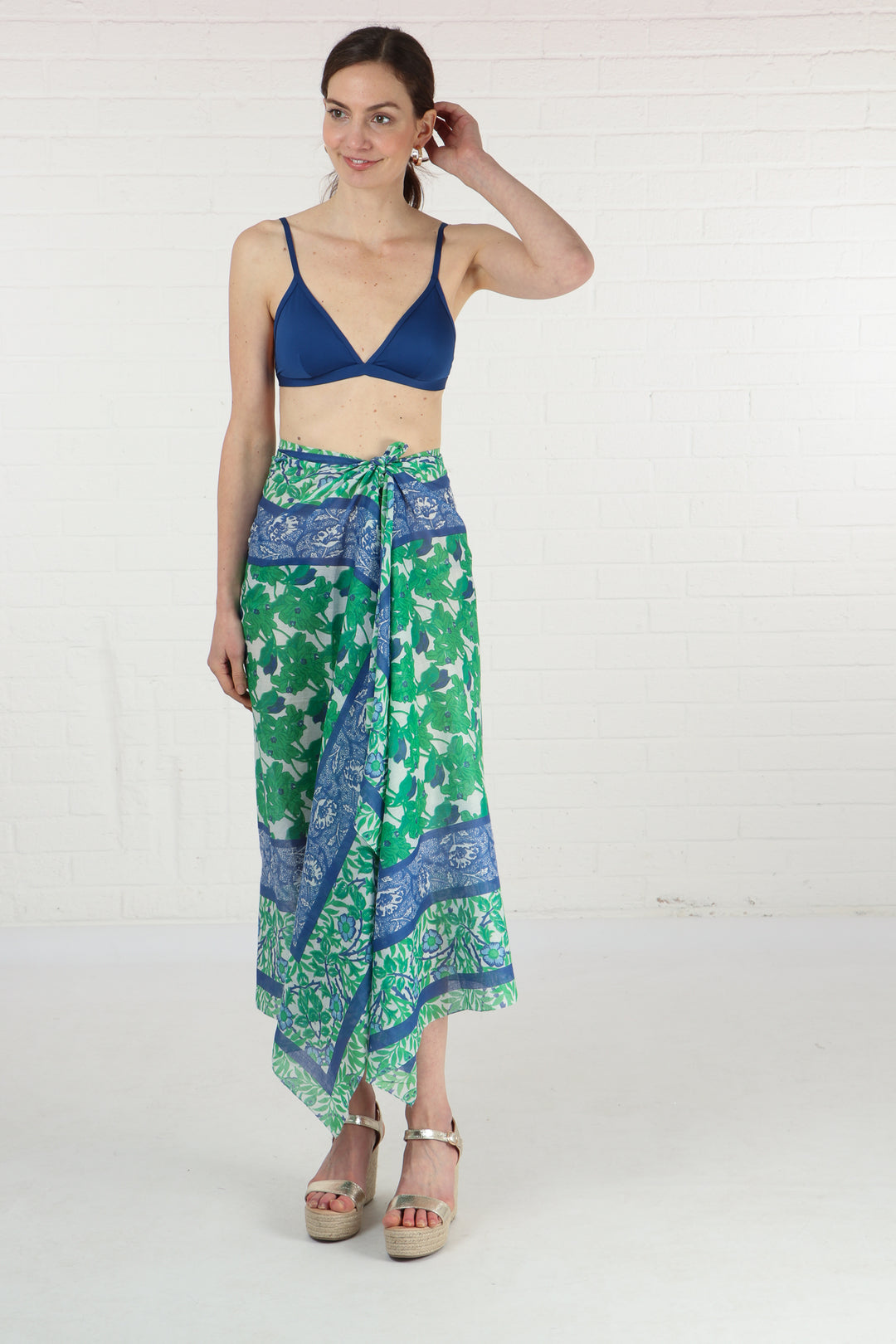 model wearing a green and blue floral print scarf as a beach sarong