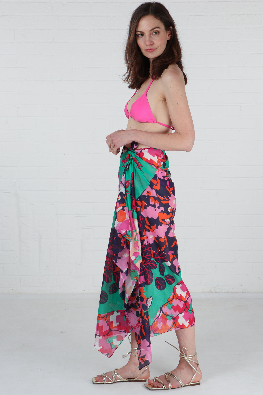 model wearing a green and pink floral bee print scarf tied around the waist to show it being worn as a beach cover up sarong