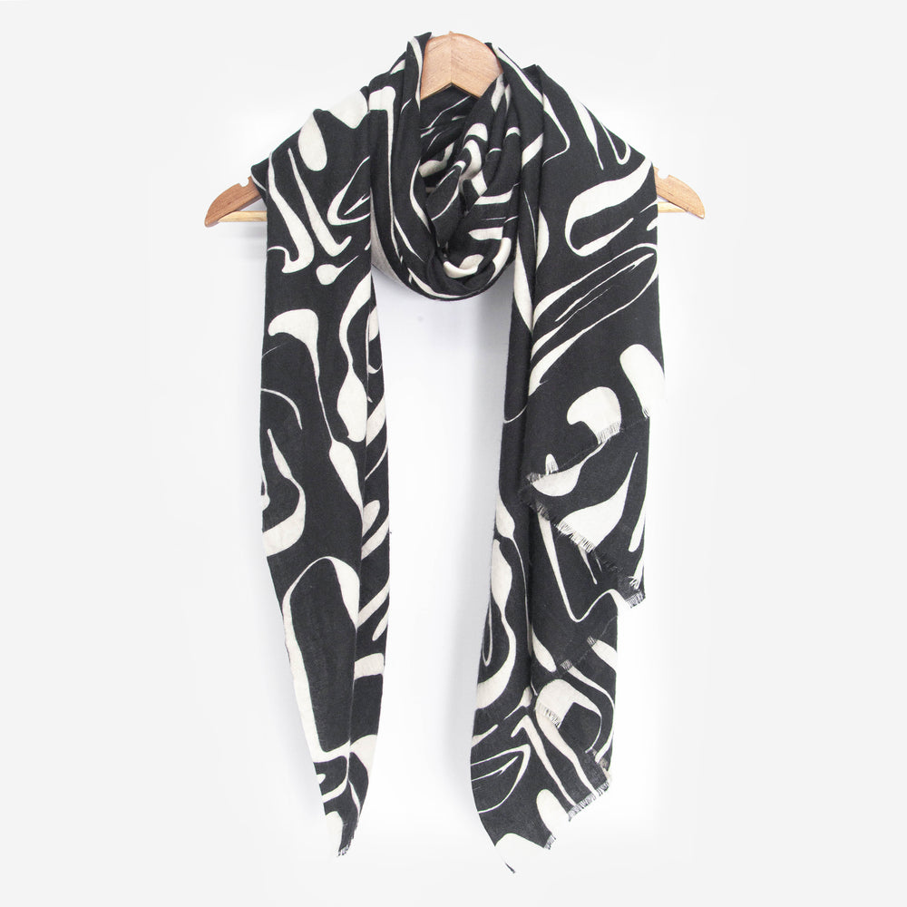 showing the black and white abstract pattern lightweight scarf draped around a coat hanger, showing how it would look when worn.