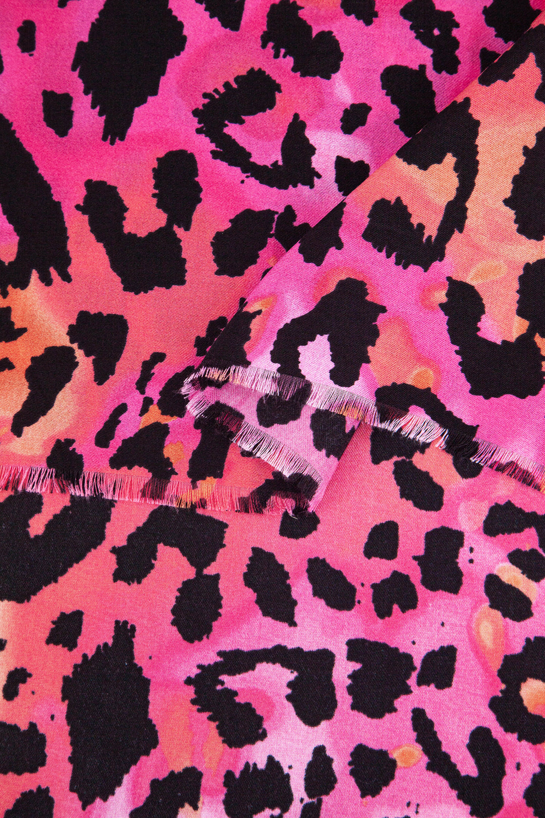 close up of the soft viscose fabric, the fuchsia, orange and black leopard print pattern is clearly shown