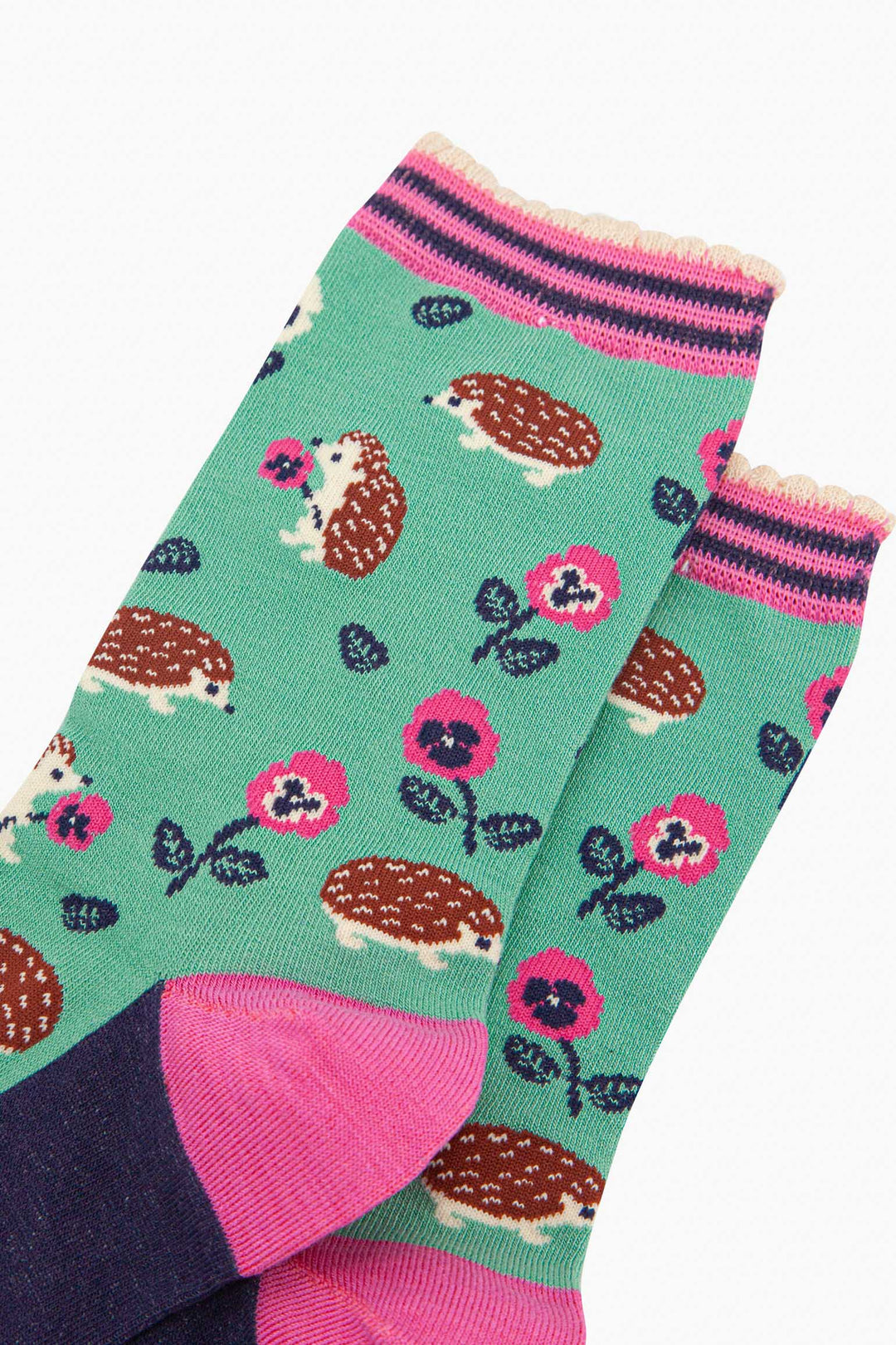 close up of the pattern. the hedgehogs are brown and beige, some are sitting holding pink pansy flowers, others are walking among the flowers. 