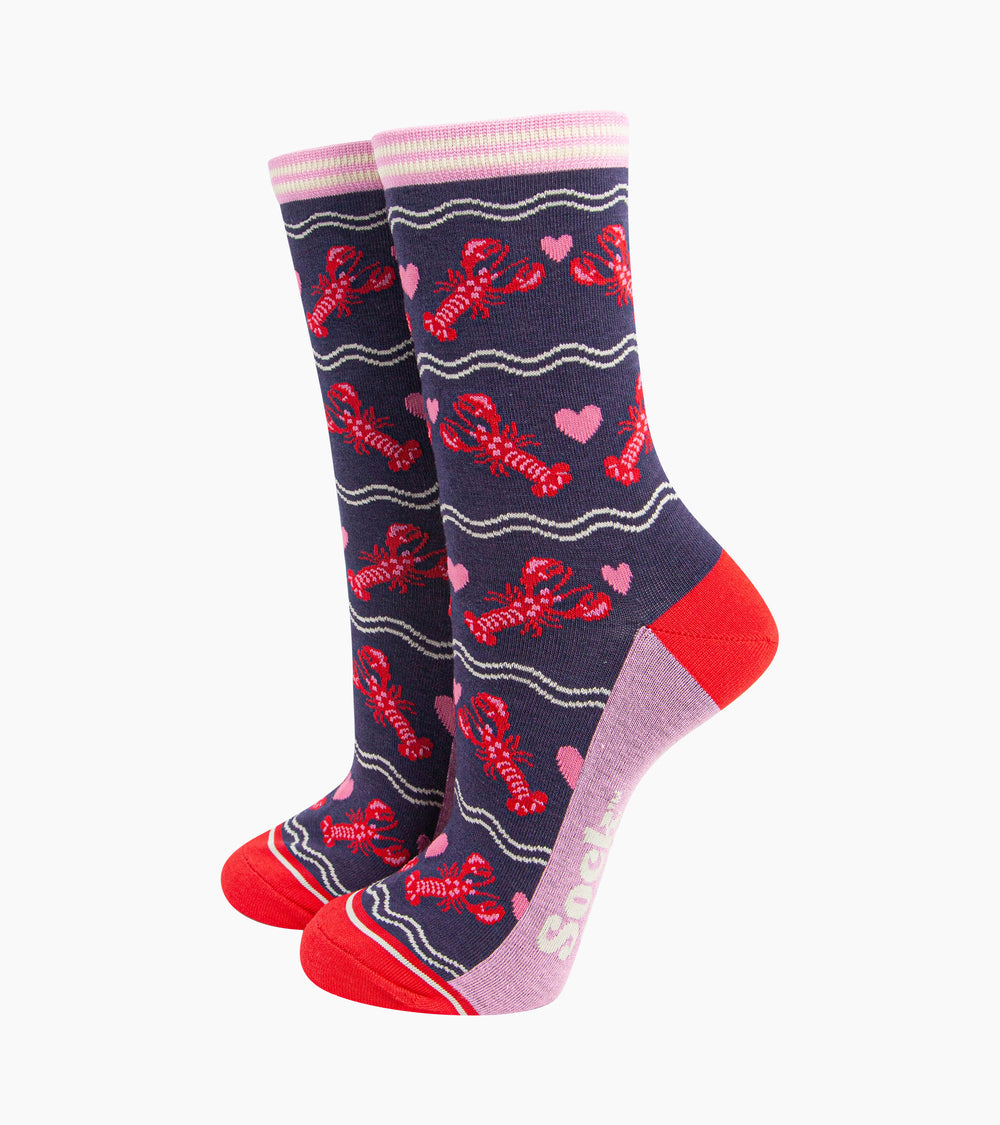 navy blue socks with a pattern of red lobsters and pink love hearts. the socks have a pink and white striped cuff and contracting red heel and toe