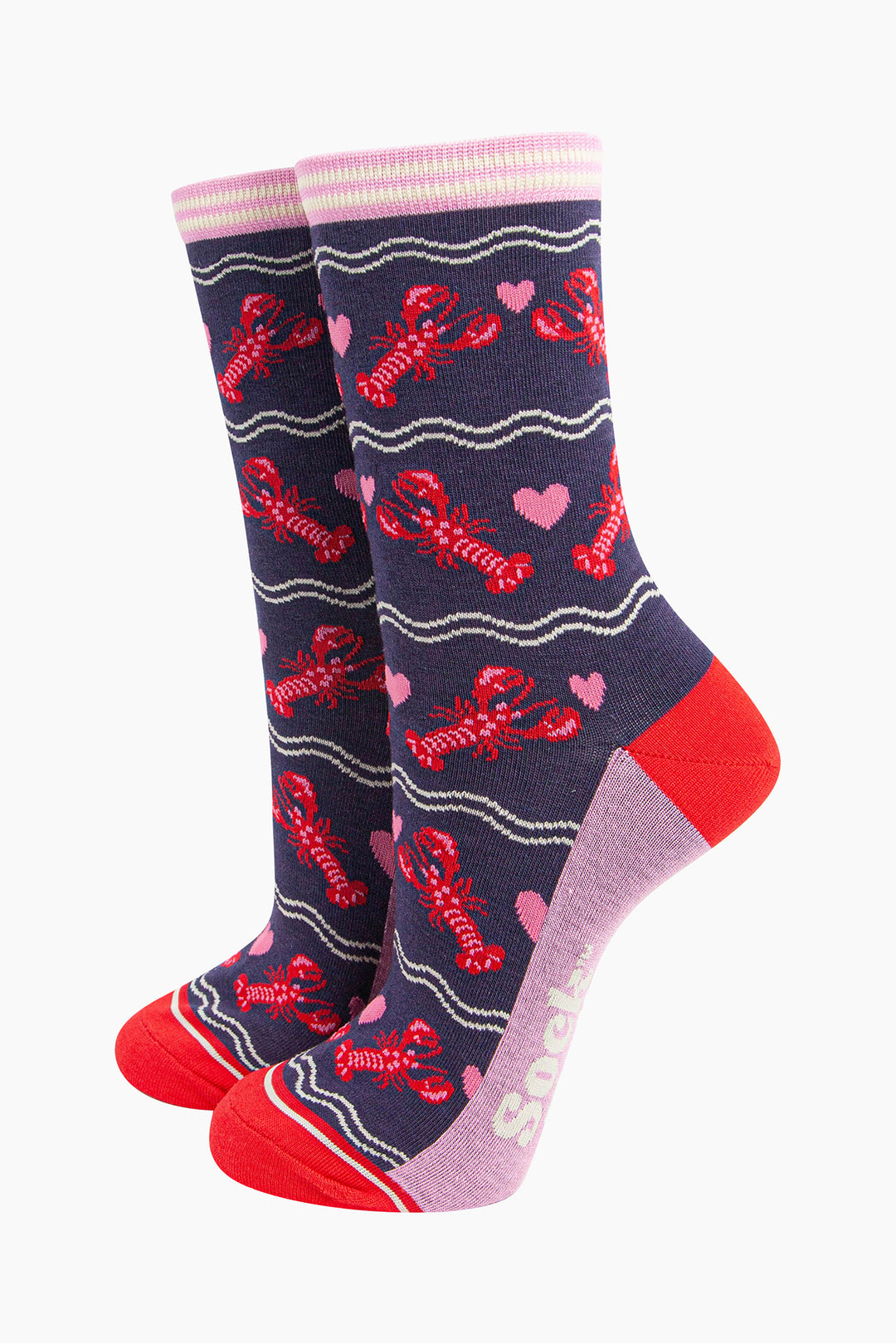 navy blue socks with a pattern of red lobsters and pink love hearts. the socks have a pink and white striped cuff and contrasting red heel and toe