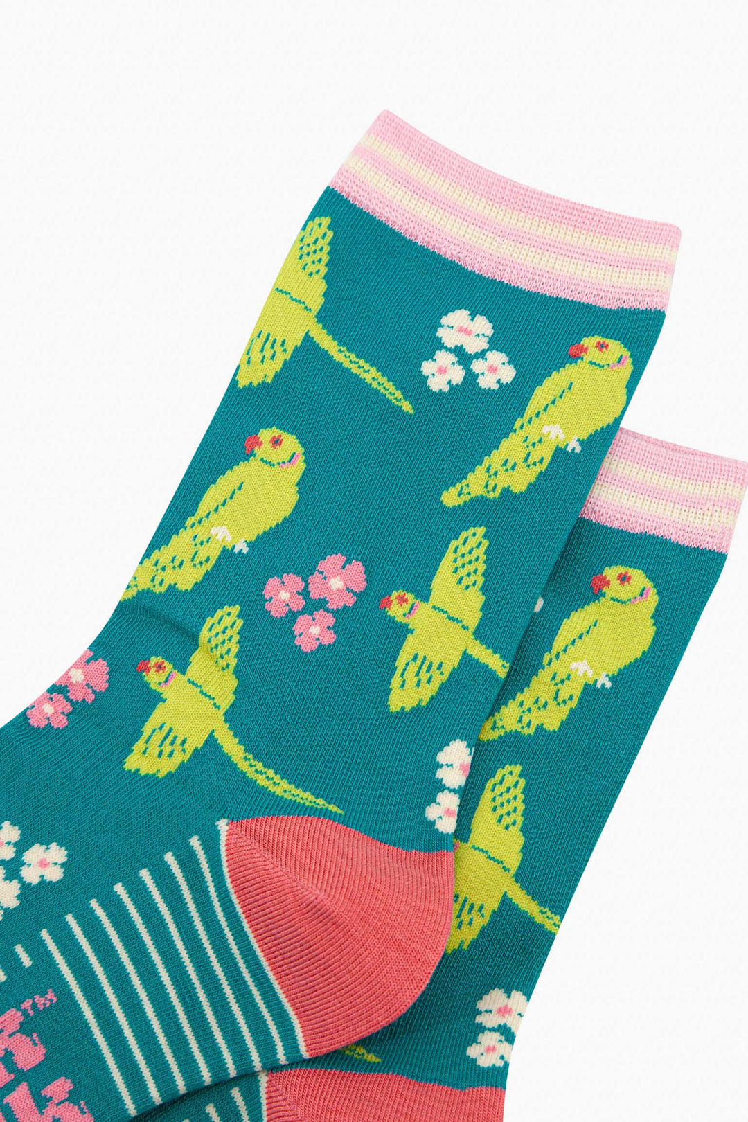 close up of the pattern. the ring necked parakeets are show flying and perching. they are lime green with red eyes and beaks. the ring on the neck is green and pink striped. interspersed among the birds are groups of three flowers in pink and white.