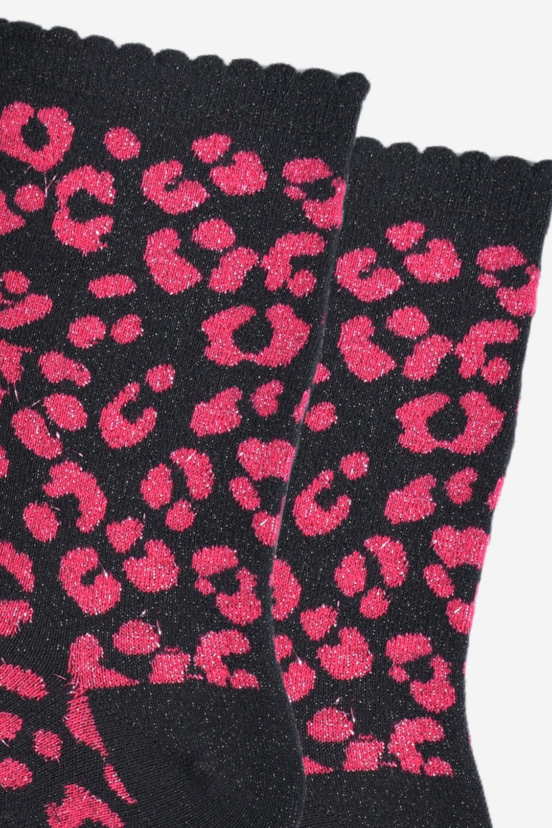 close up of the pink leopard print pattern on the socks, there is a visible silver glitter sparkle all over the design. the pink print contrasts with the black base of the socks