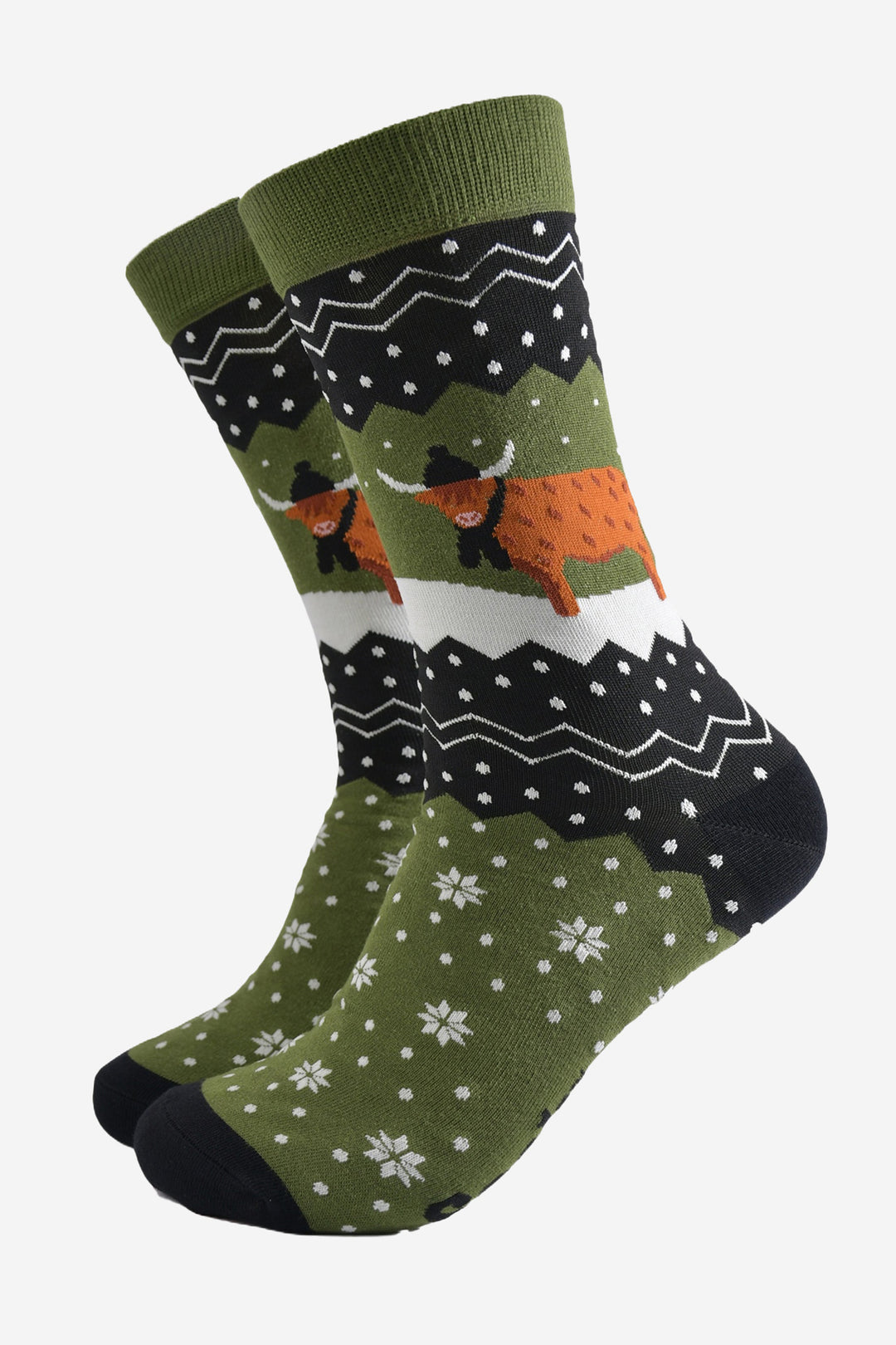 green and black bamboo socks with a fair isle zig zag and snowflake pattern, featuring a highland cow standing in a snowy field wearing a black winter hat