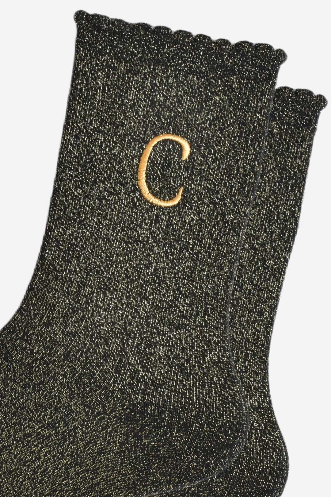 close up of the gold embroidered capital letter c on the ankle of the socks