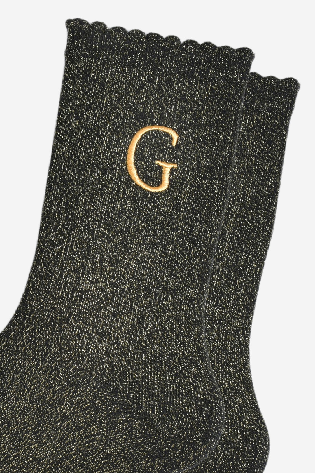 close up of the gold embroidered capital letter g on the ankle of the socks