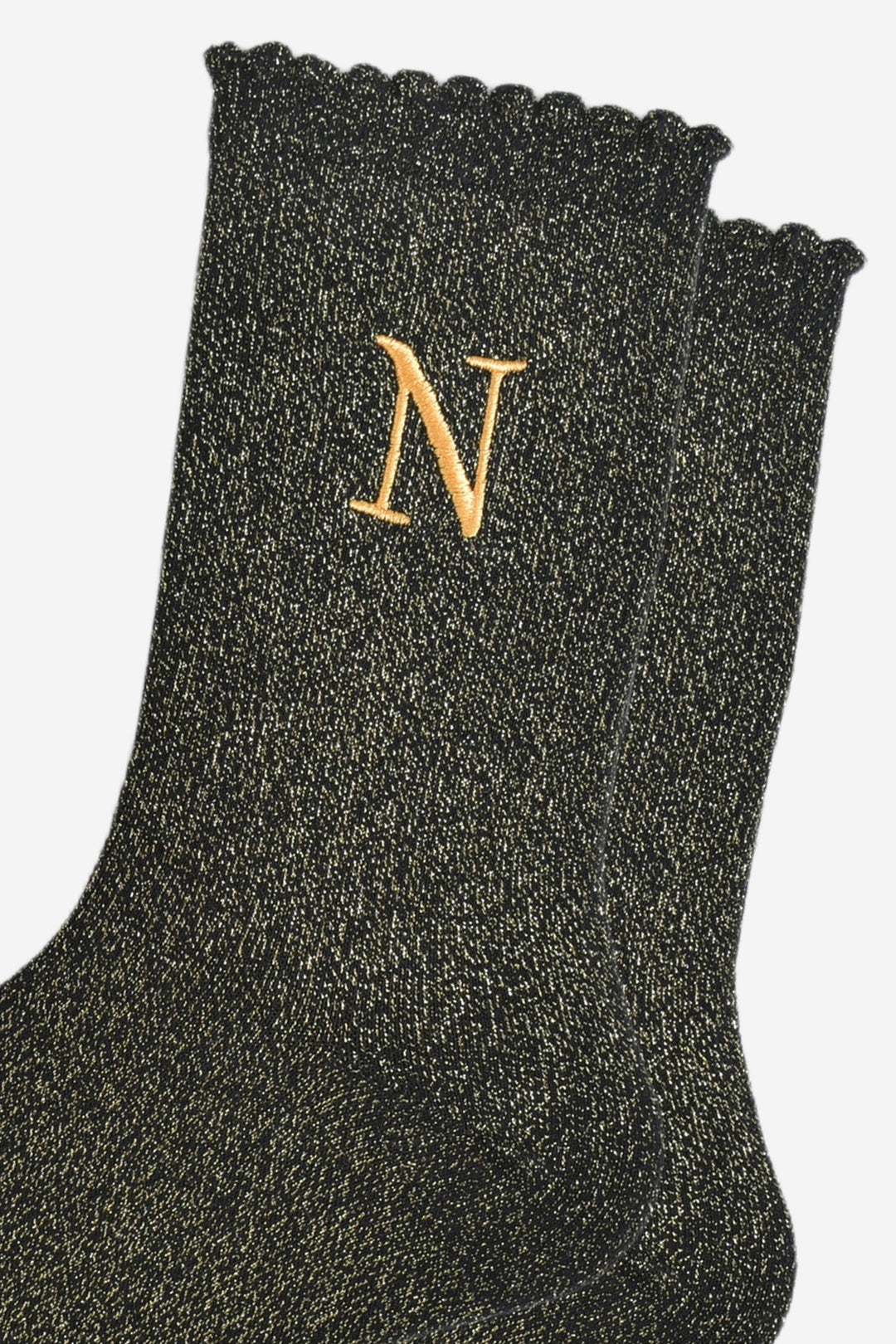 close up of the gold embroidered capital letter n on the ankle of the socks