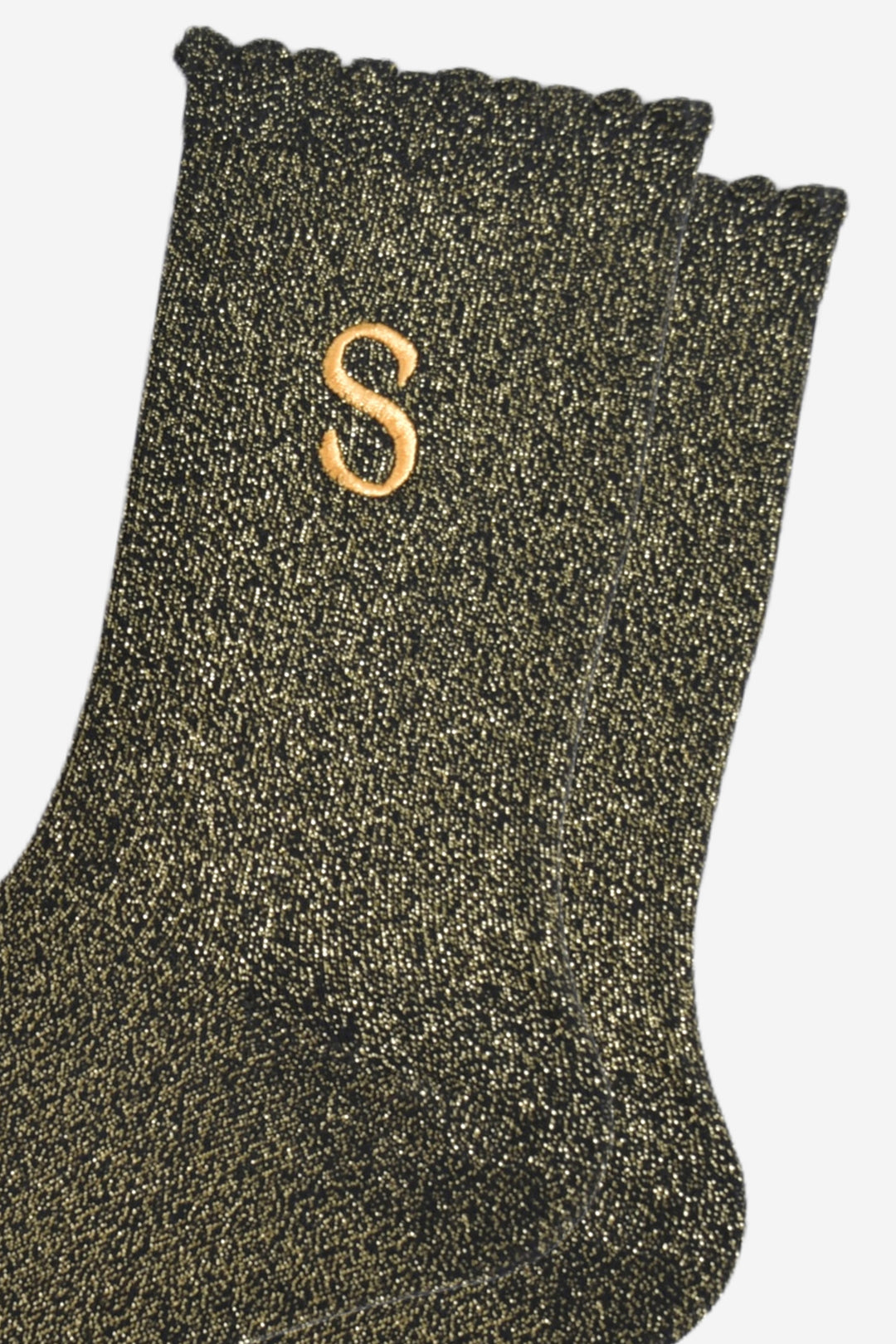 close up of the gold embroidered capital letter s on the ankle of the socks