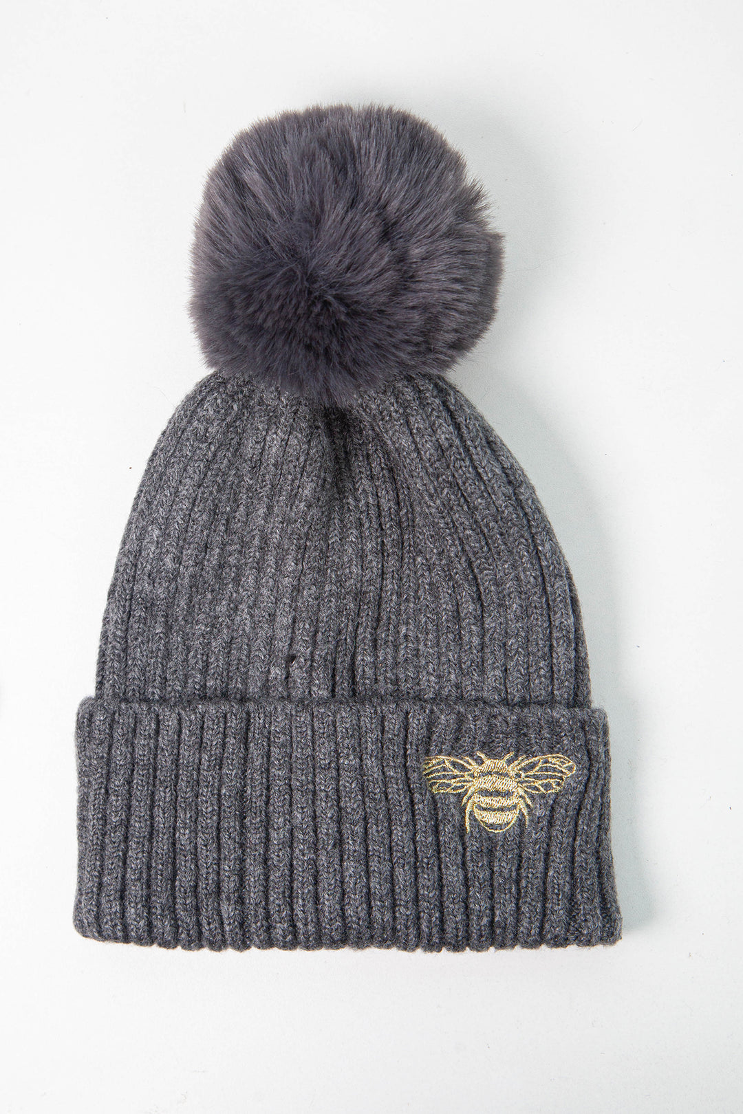 dark grey ribbed beanie hat with a pom pom on top and a gold embroidered bee motif on the cuff of the hat