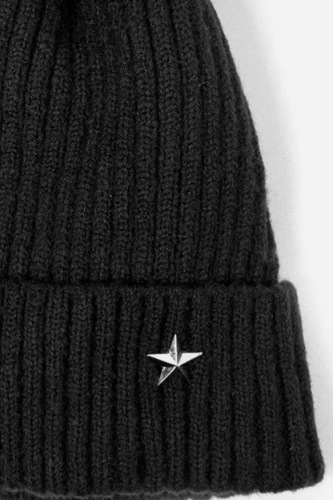 close up of the silver metal star on the rim of the ribbed black hat