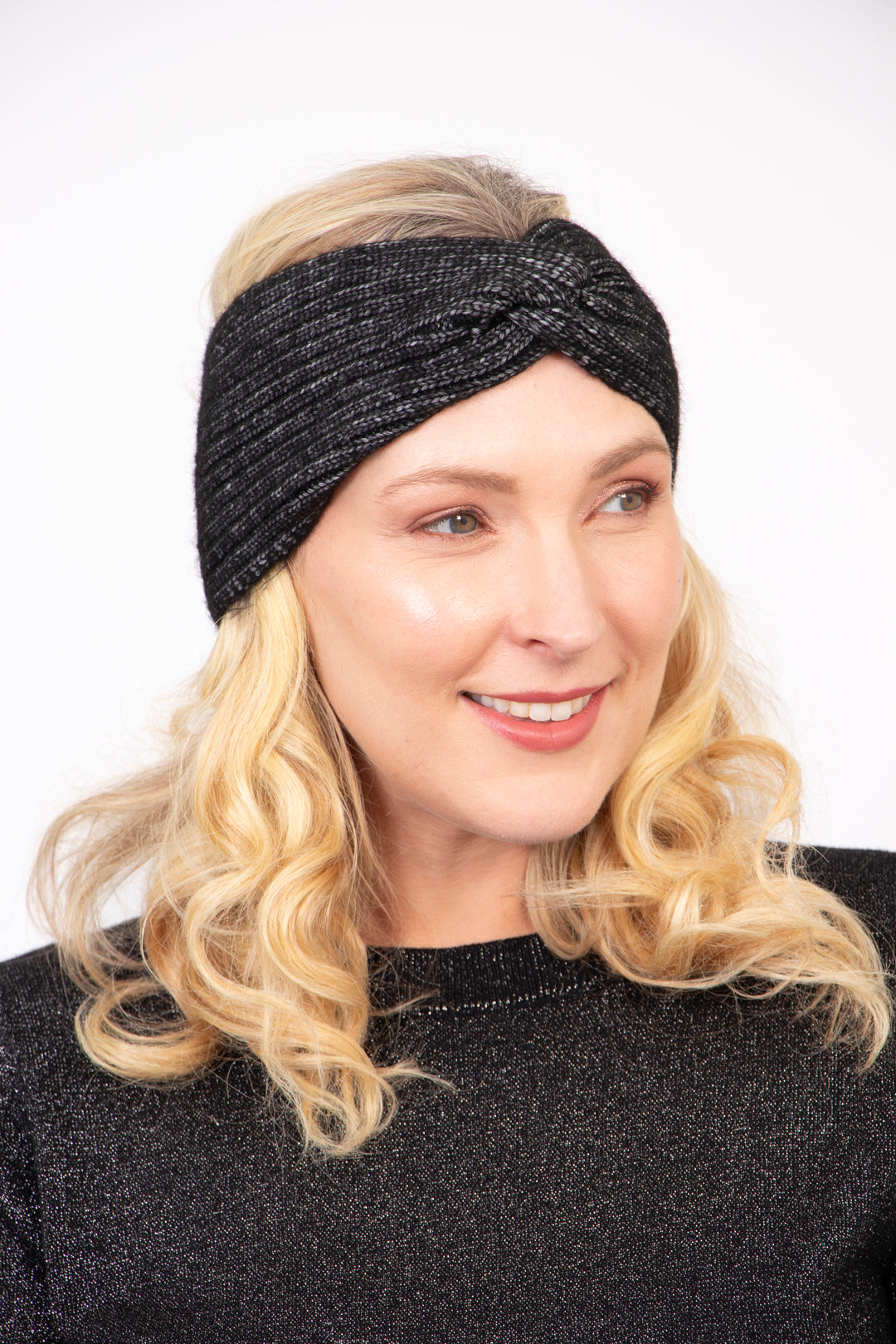 model wearing a black knitted twist front headband, the band covers the ears and forehead