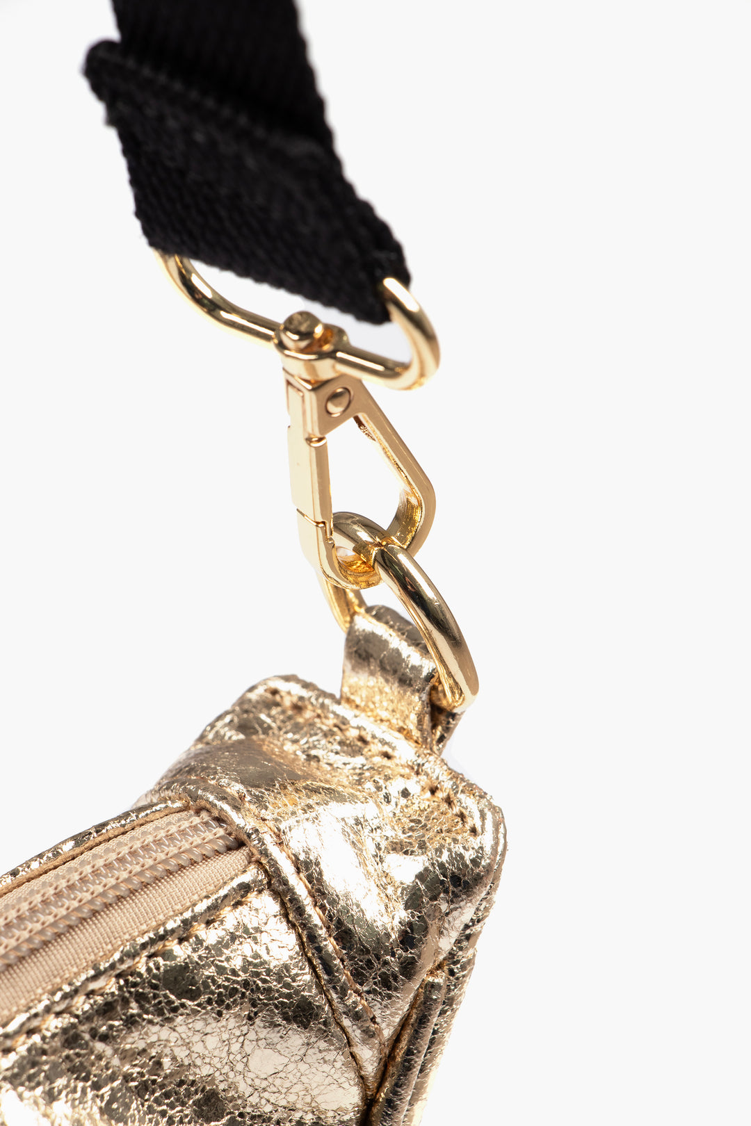 close up of the gold coloured snap hook attachment on the end of the bag strap, showing how it connects to the bag