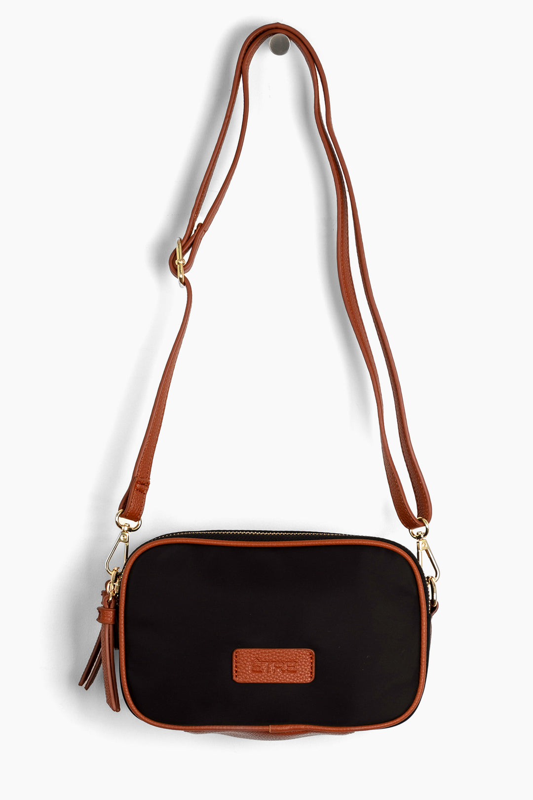 black crossbody bag with tan faux leather accents and a detachable strap