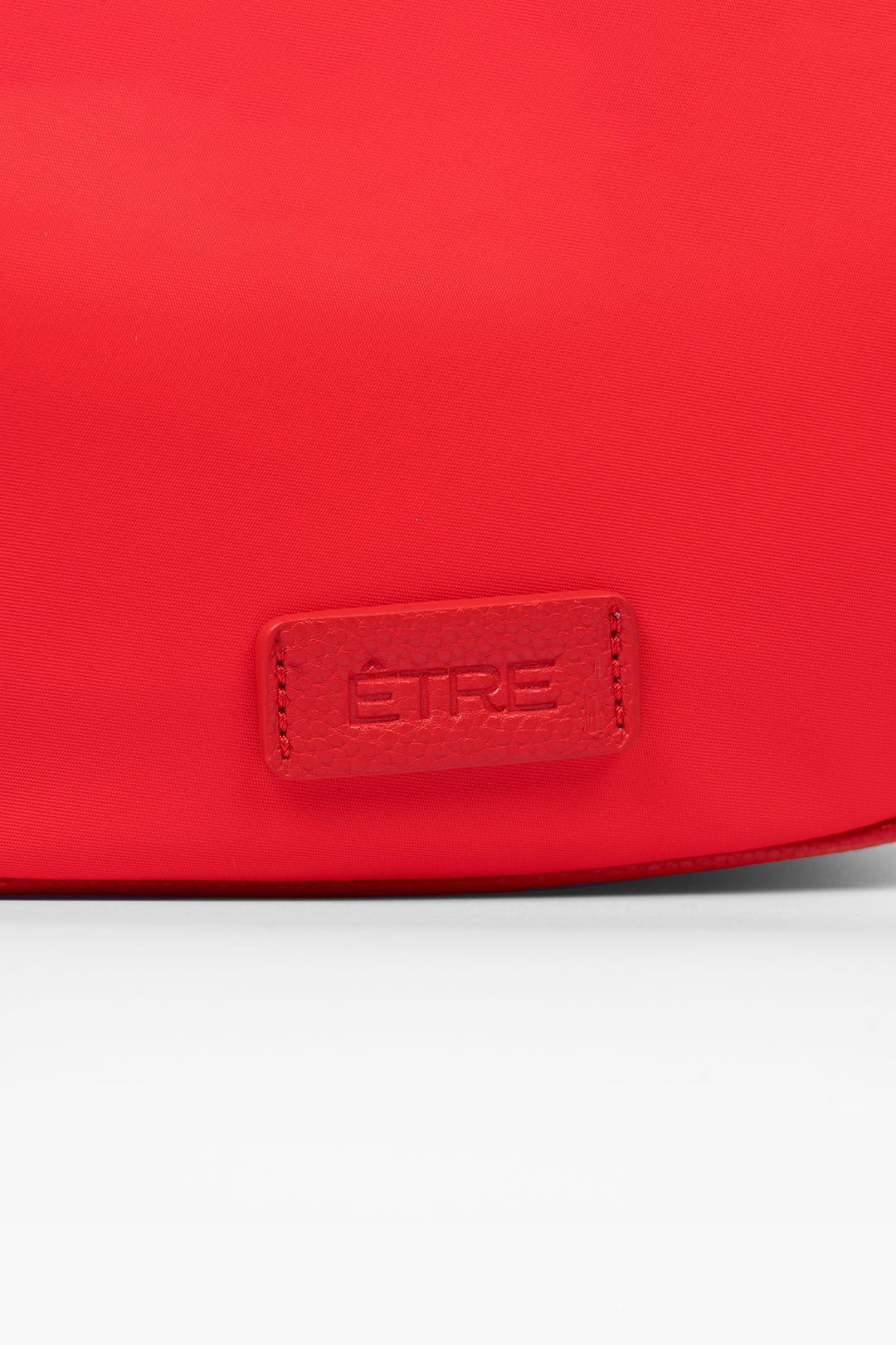 quinn-half-moon-crossbody-bag-red-nylon-close-up-etre-logo
