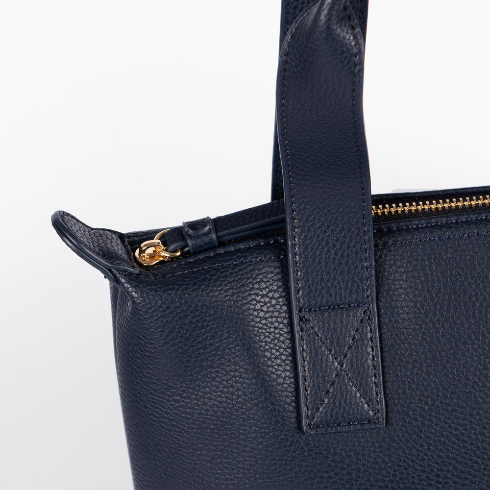 close up of the top of the bag, showing clearly the gold zip closure main compartment and carry handles on the top.