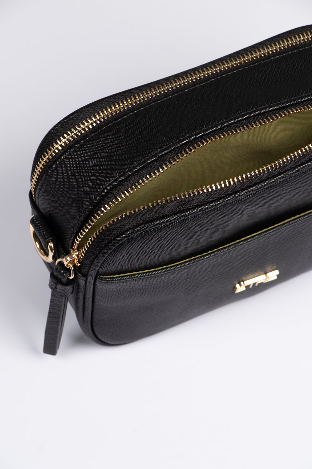 close up of the crossbody bag, showing two zip closing compartments on the top of the bag and one front pocket