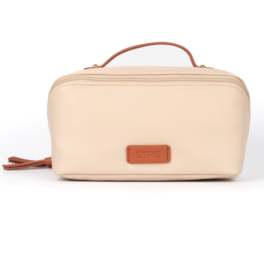 cream vanity case with tan faux leather accents and top handle. the cosmetics bag has zip fastening closure.