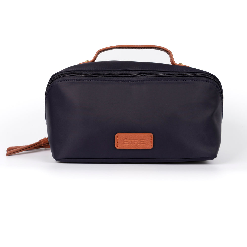 navy blue vanity case with tan faux leather accents and top handle. the cosmetics bag has zip fastening closure.