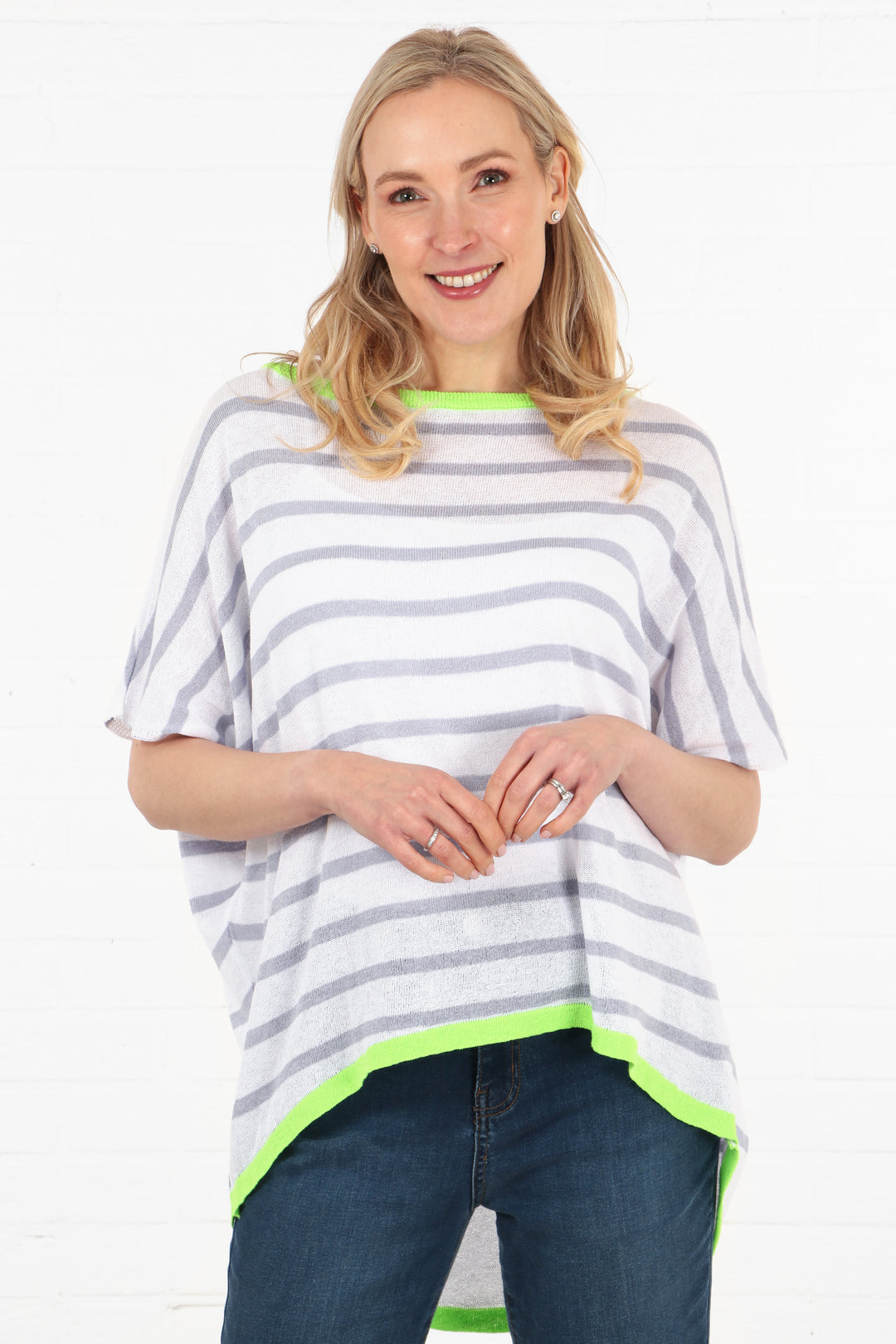 model wearing a white cotton batwing jumper with short sleeves and lilac stipes. the cotton jumper has a neon green contrasting hem and neck stripe