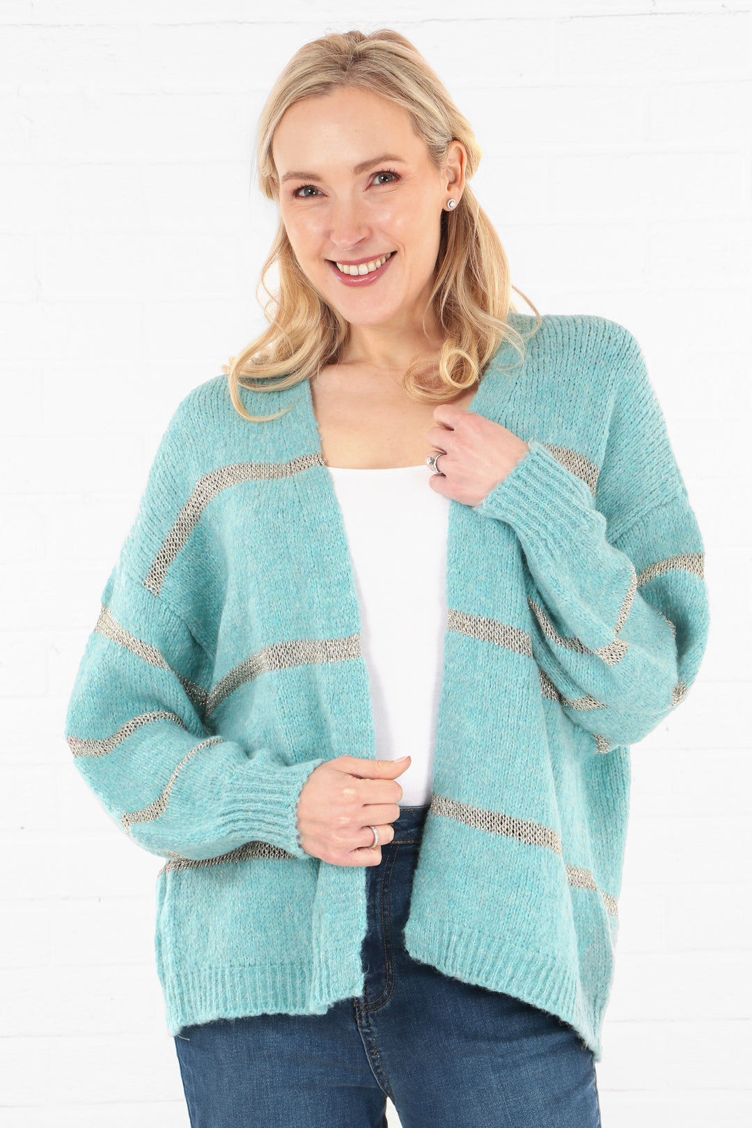 model wearing a mint blue green open front knit cardigan with a horizontal knit gold stripe throughout