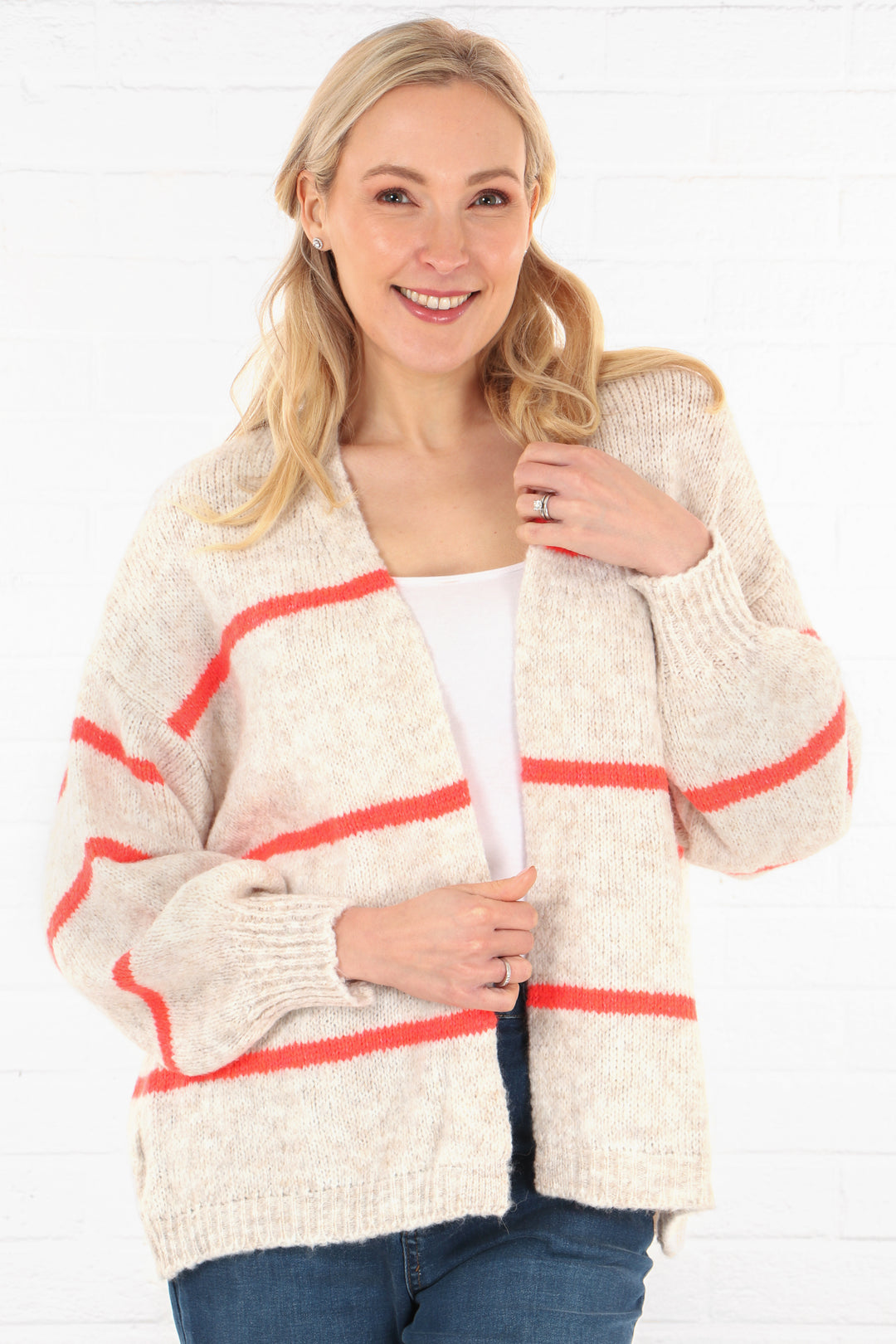 model wearing a cream knitted open front cardigan with a coral orange thin stripe detail 