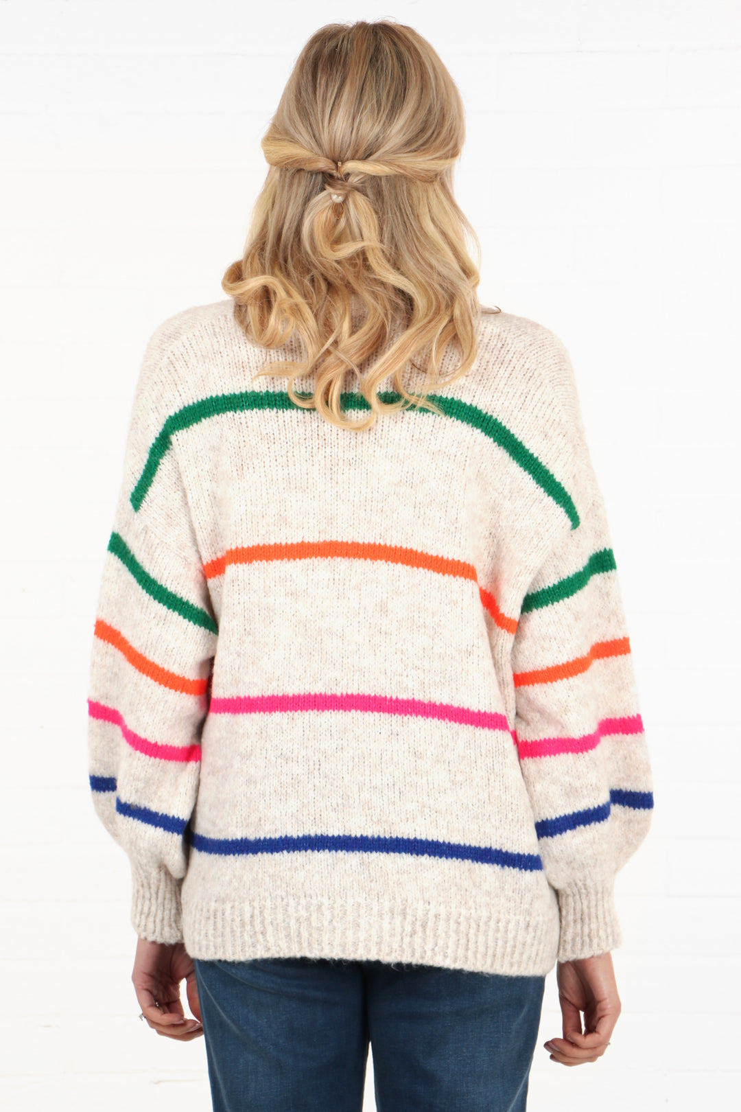 model showing the back of the cream cardigan showing the multicoloured stripes